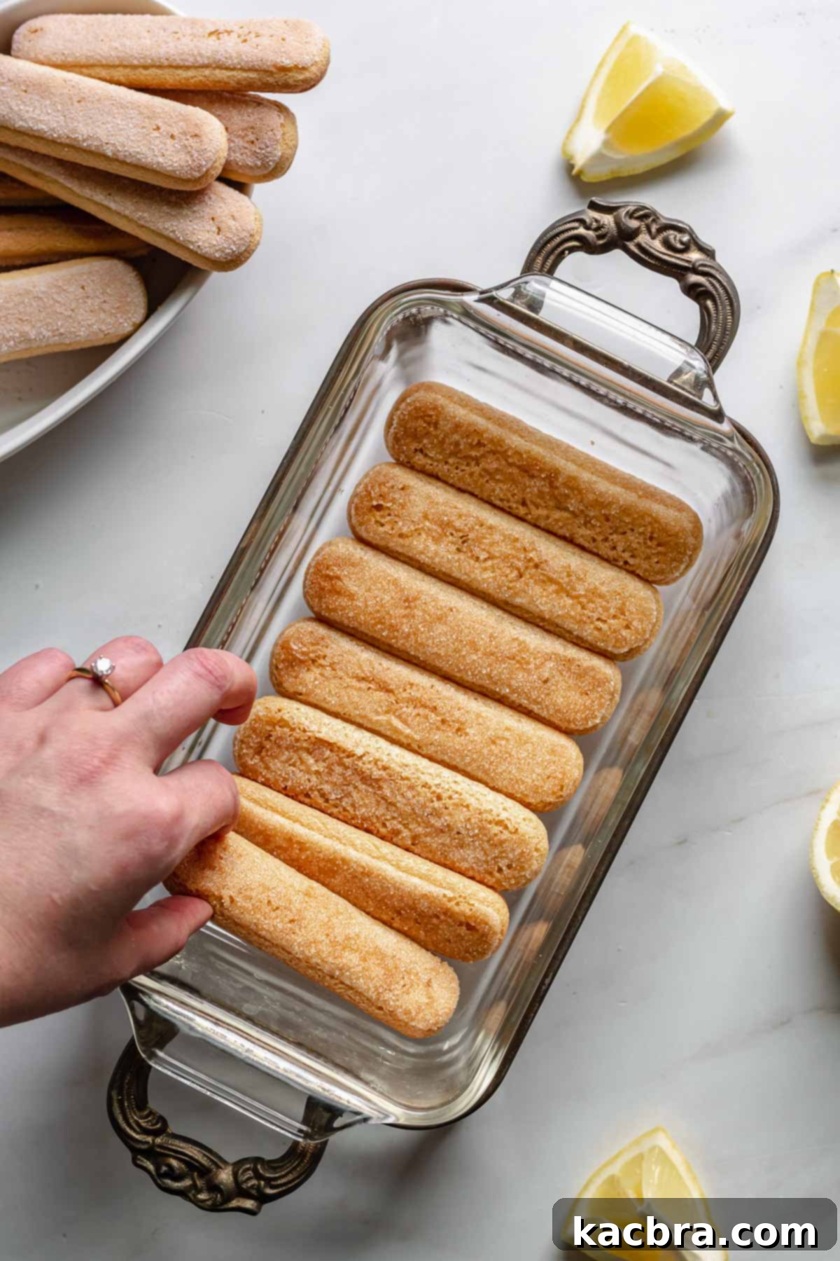 Carefully layering dipped lady fingers in the bottom of a loaf pan.