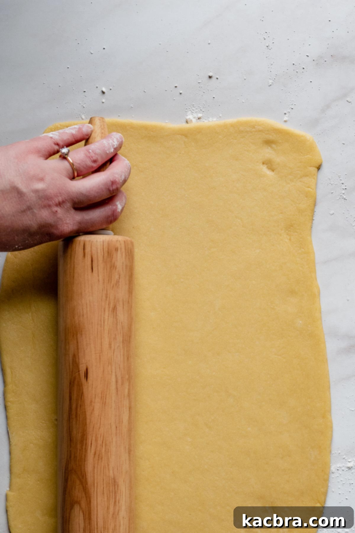 A rolling pin is actively rolling out the babka dough on a lightly floured surface, shaping it into a perfect 10x14 inch rectangle, ready for the filling.