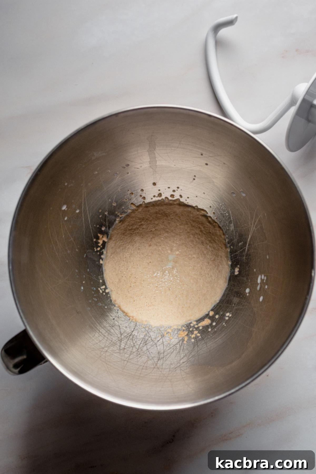Warm milk, sugar, and active dry yeast bubbling gently in a bowl, showing successful activation and readiness for dough making.