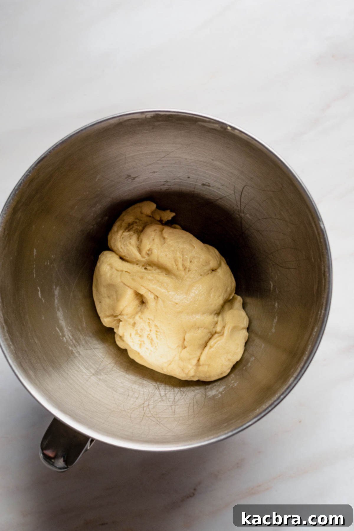 A perfectly smooth, elastic, and well-combined dough ball resting in a bowl, ready for its initial rise.