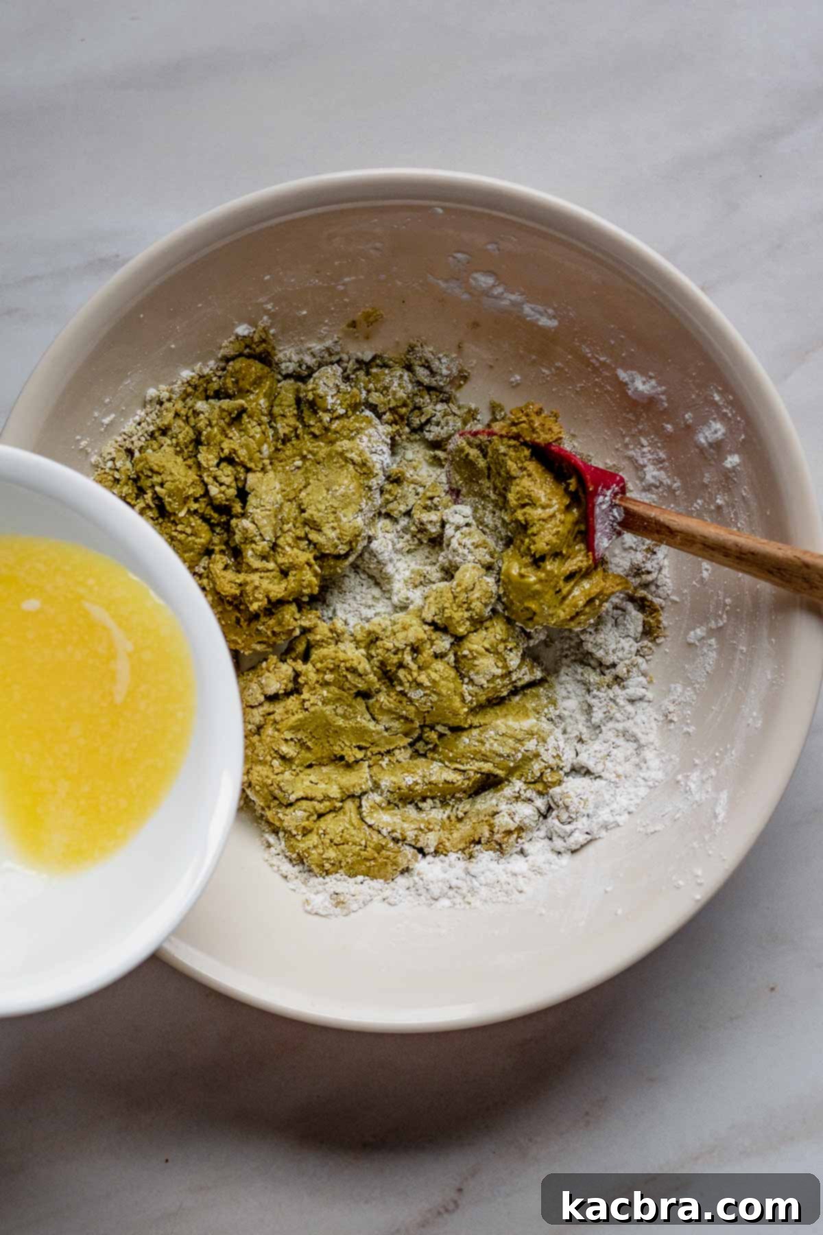 Melted butter combined with pistachio butter, powdered sugar, and almond extract in a bowl, ready for mixing to create the babka filling.