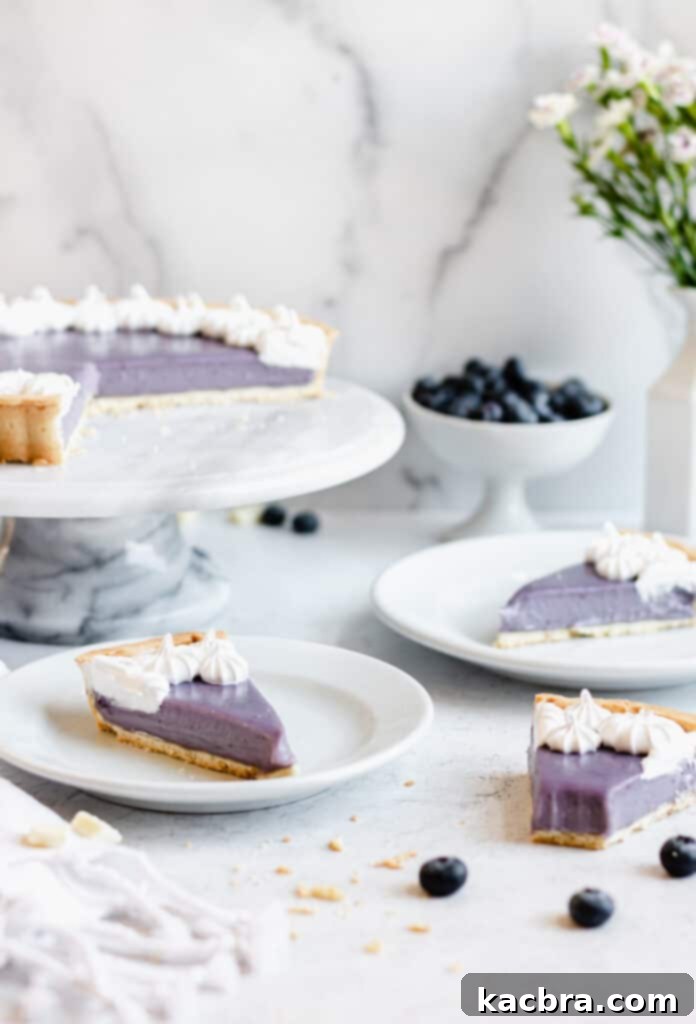 A Blueberry White Chocolate Ganache Tart with three slices removed and two placed on plates. One slice on the table shows a bite taken out, highlighting its creamy texture.