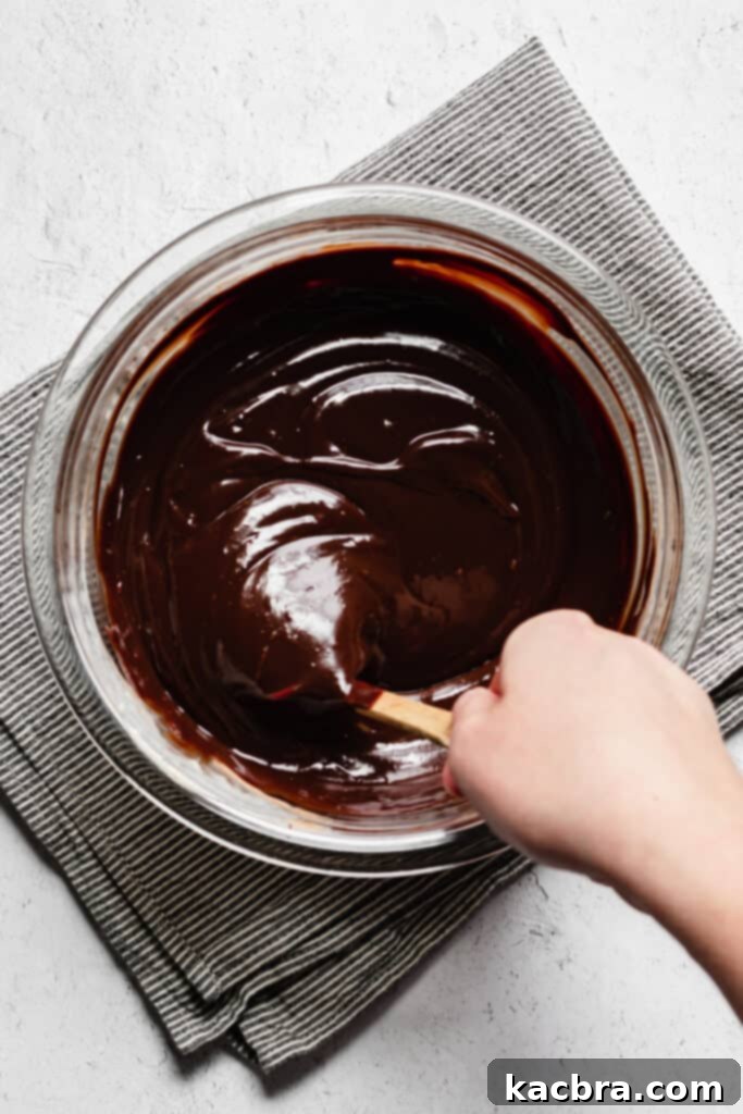 Smooth, glossy chocolate ganache being stirred until fully emulsified.