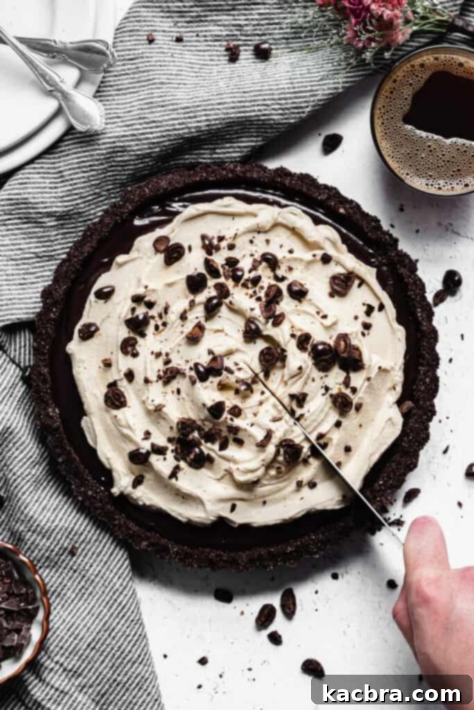 Espresso whipped cream being scooped onto the set chocolate ganache tart.