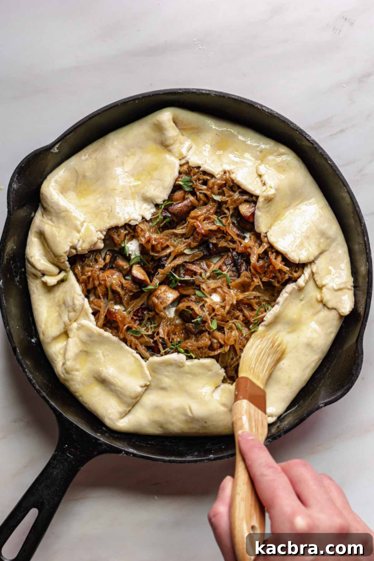 Sweet Caramelized Onion & Mushroom Potato Tart 11 Egg wash being brushed onto the dough.
