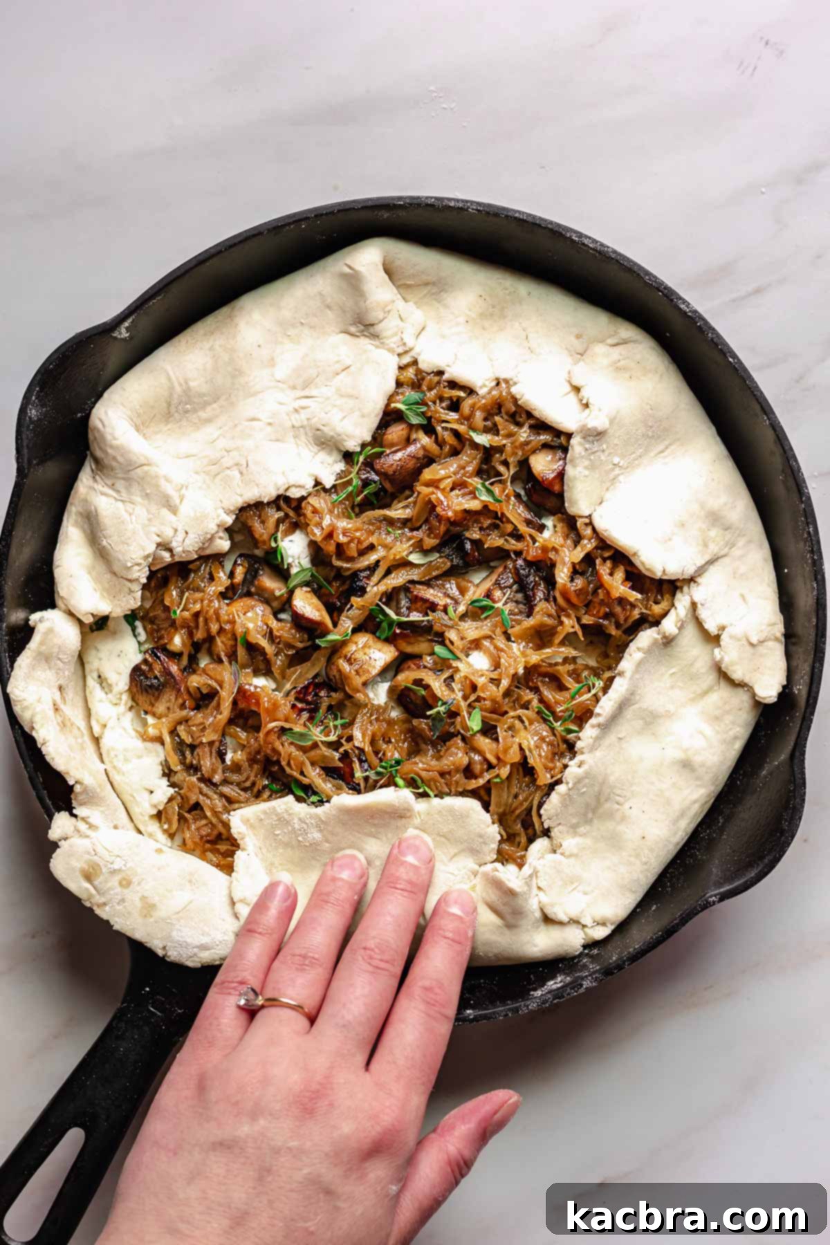 Sweet Caramelized Onion & Mushroom Potato Tart 10 Hands folding the crust inwards.