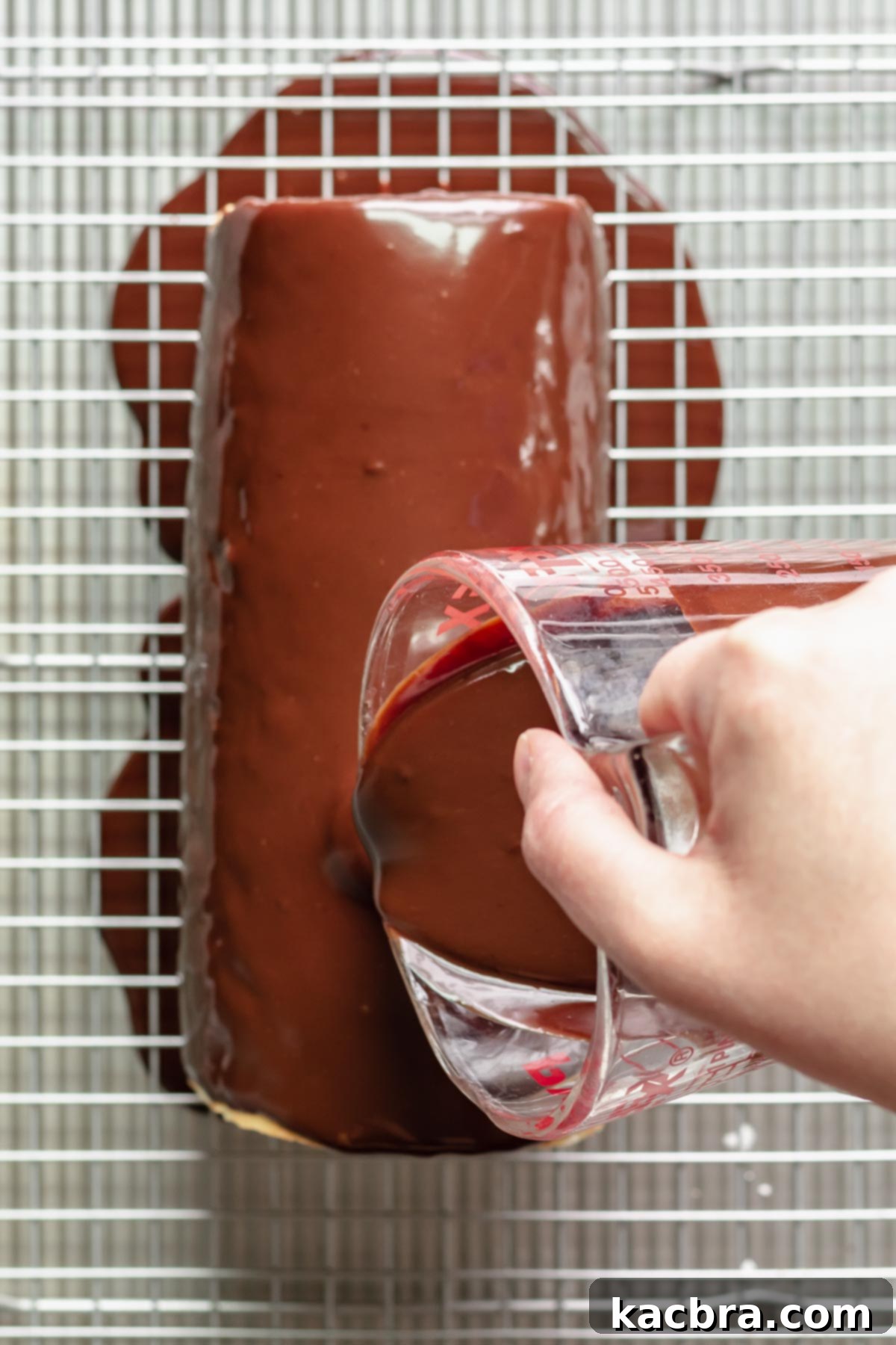 Chocolate ganache being poured onto the Swiss roll.