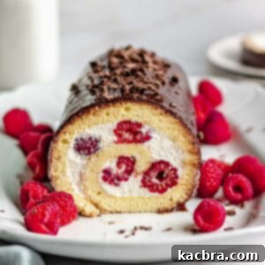 Swiss roll cake with a slice removed and raspberries scattered around the platter.