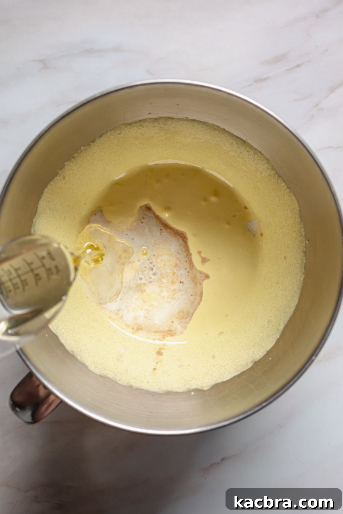 Raspberry and Vanilla Swirl Cake with Decadent Chocolate Ganache 5 Oil being poured into creamed sugar and egg yolks.