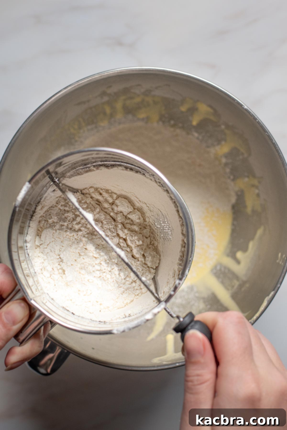Raspberry and Vanilla Swirl Cake with Decadent Chocolate Ganache 6 Flour sifting into batter.