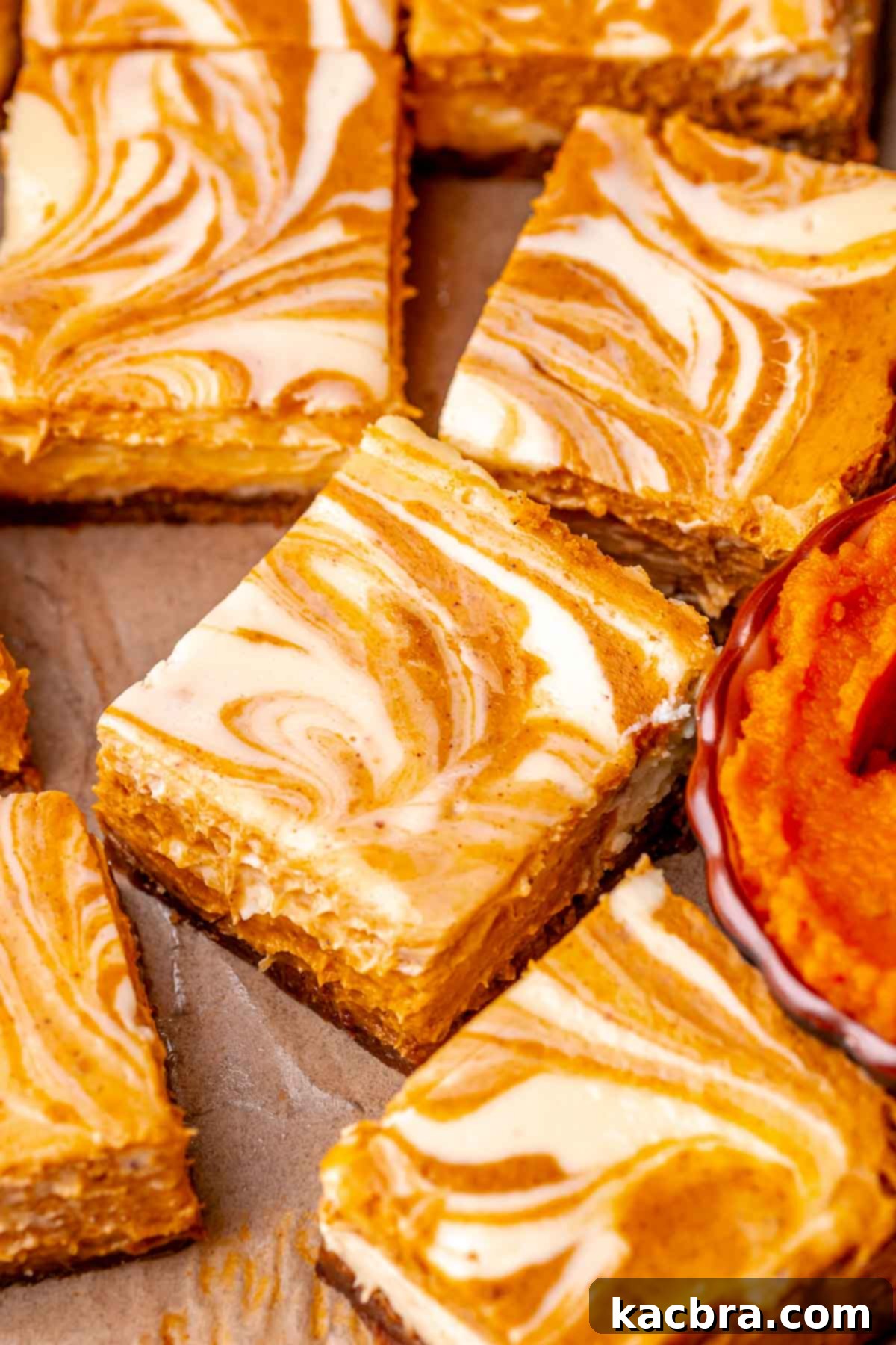 Perfectly sliced pumpkin cheesecake bars arranged neatly on parchment paper, highlighting their beautiful swirled tops and thick crusts.