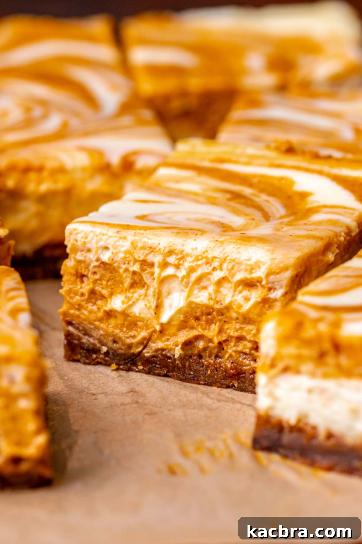 Several perfectly sliced pumpkin cheesecake bars neatly arranged on parchment paper, ready to be served or stored.