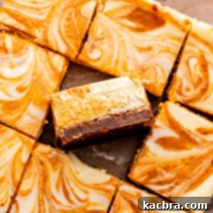 Sliced pumpkin cheesecake bars, with one bar casually tilted on its side, showcasing the beautiful swirl and the gingersnap crust.