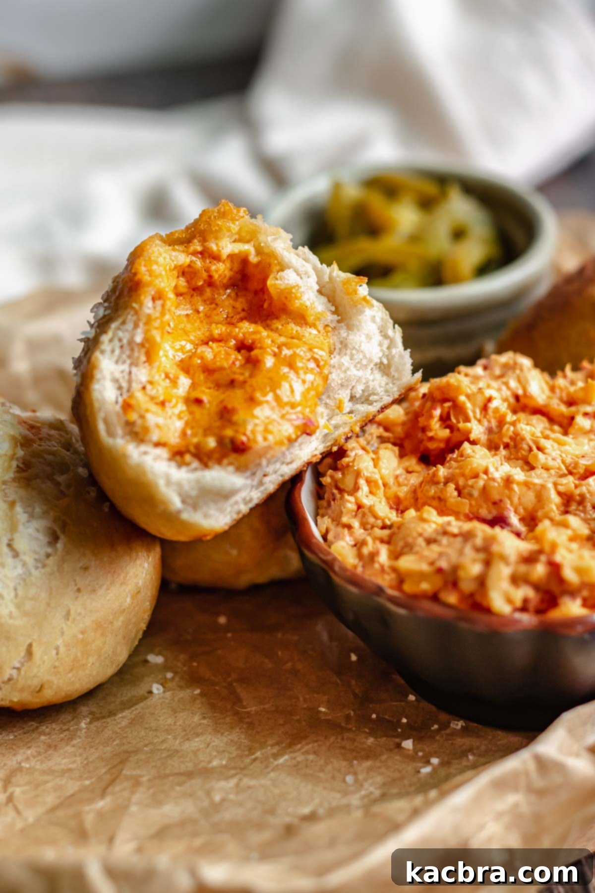 Savory Pimento Pretzel Twists 3 A pimento cheese stuffed pretzel bite broken in half, revealing the melted cheesy filling, placed next to a small bowl of pimento cheese.