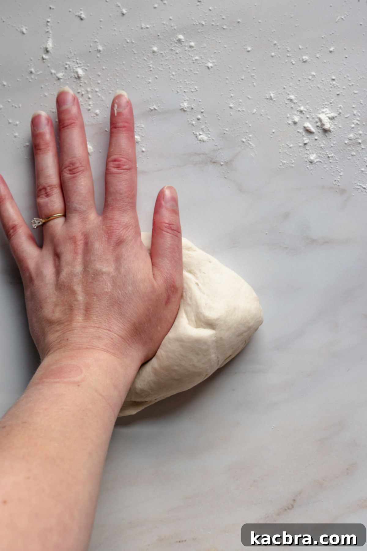 Savory Pimento Pretzel Twists 6 A hand kneading soft pretzel dough on a clean surface.