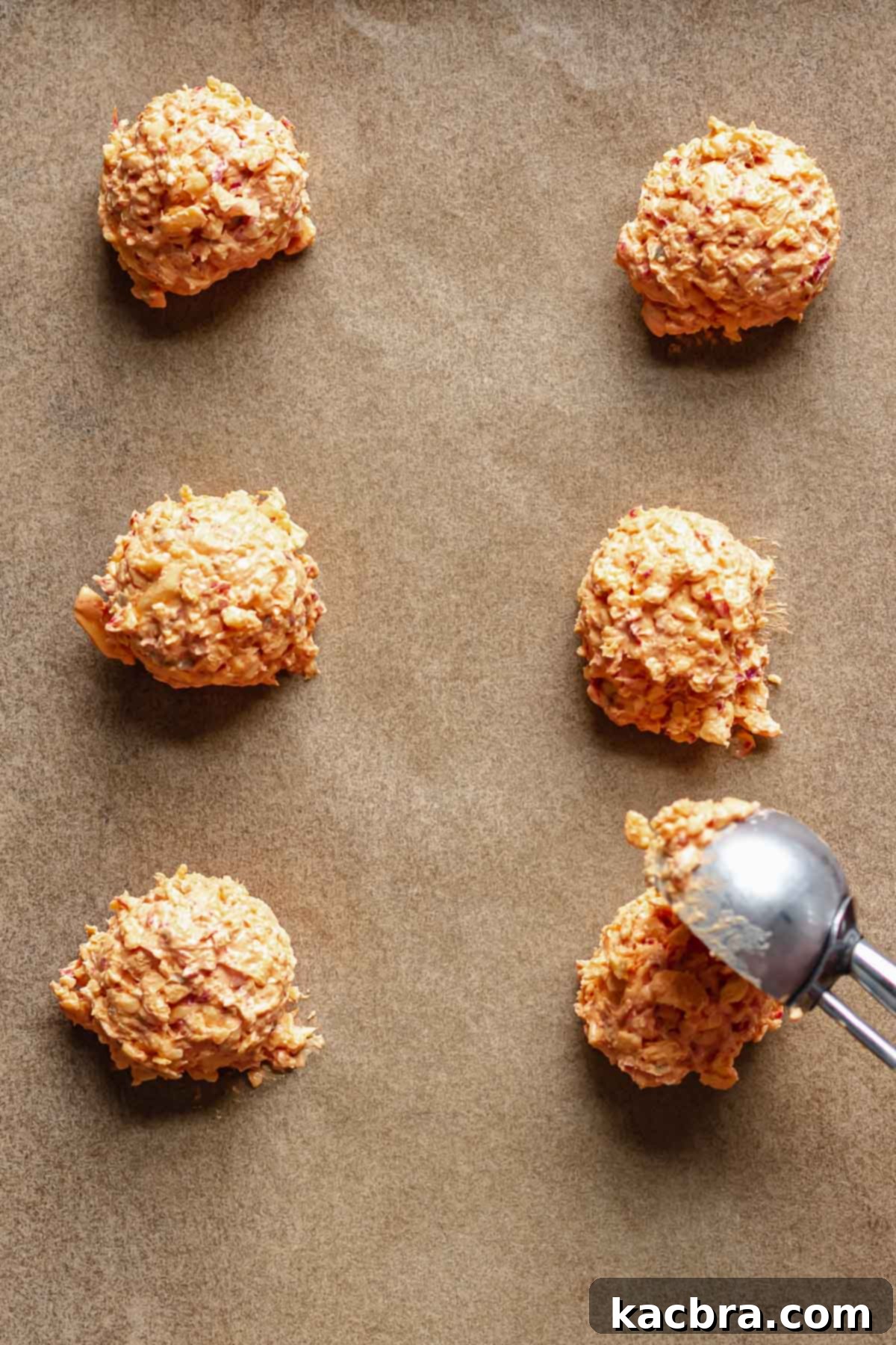 Savory Pimento Pretzel Twists 8 A cookie scoop forming balls of pimento cheese onto a parchment-lined tray for freezing.