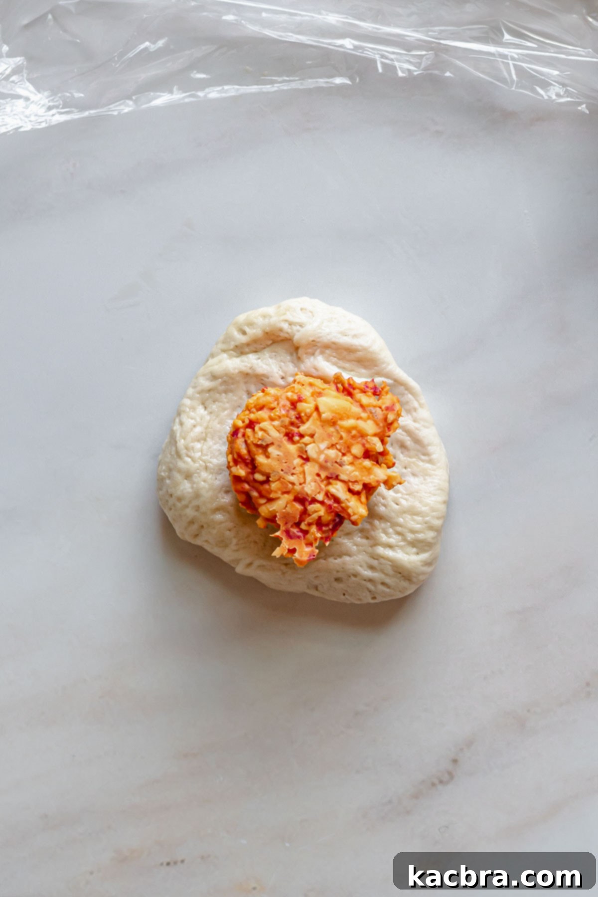 Savory Pimento Pretzel Twists 9 A pimento cheese ball placed on a slightly flattened piece of pretzel dough.