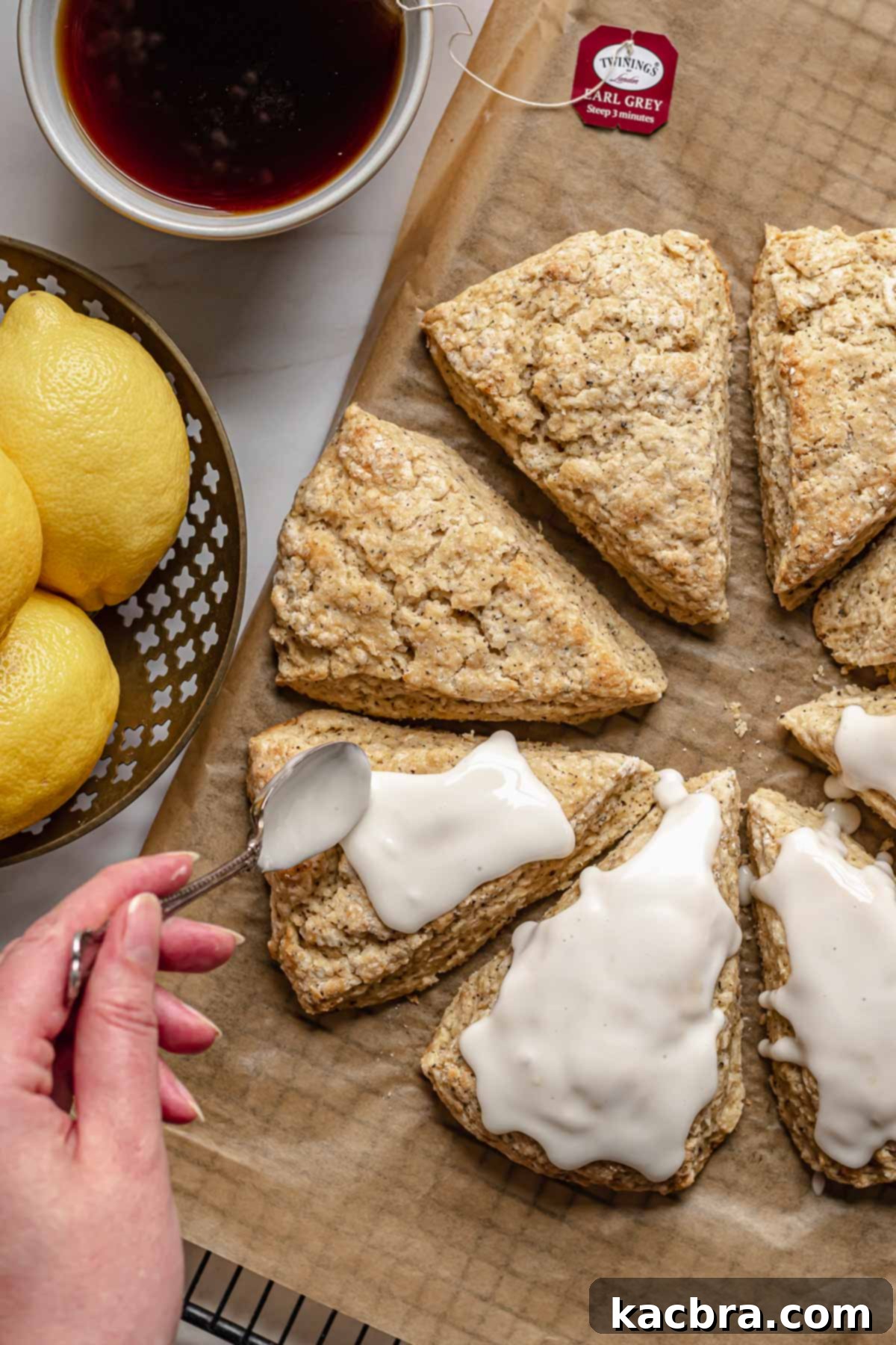 Fragrant Earl Grey Scones with Zesty Lemon Drizzle 10 A hand spoons lemon glaze on to the baked scones.