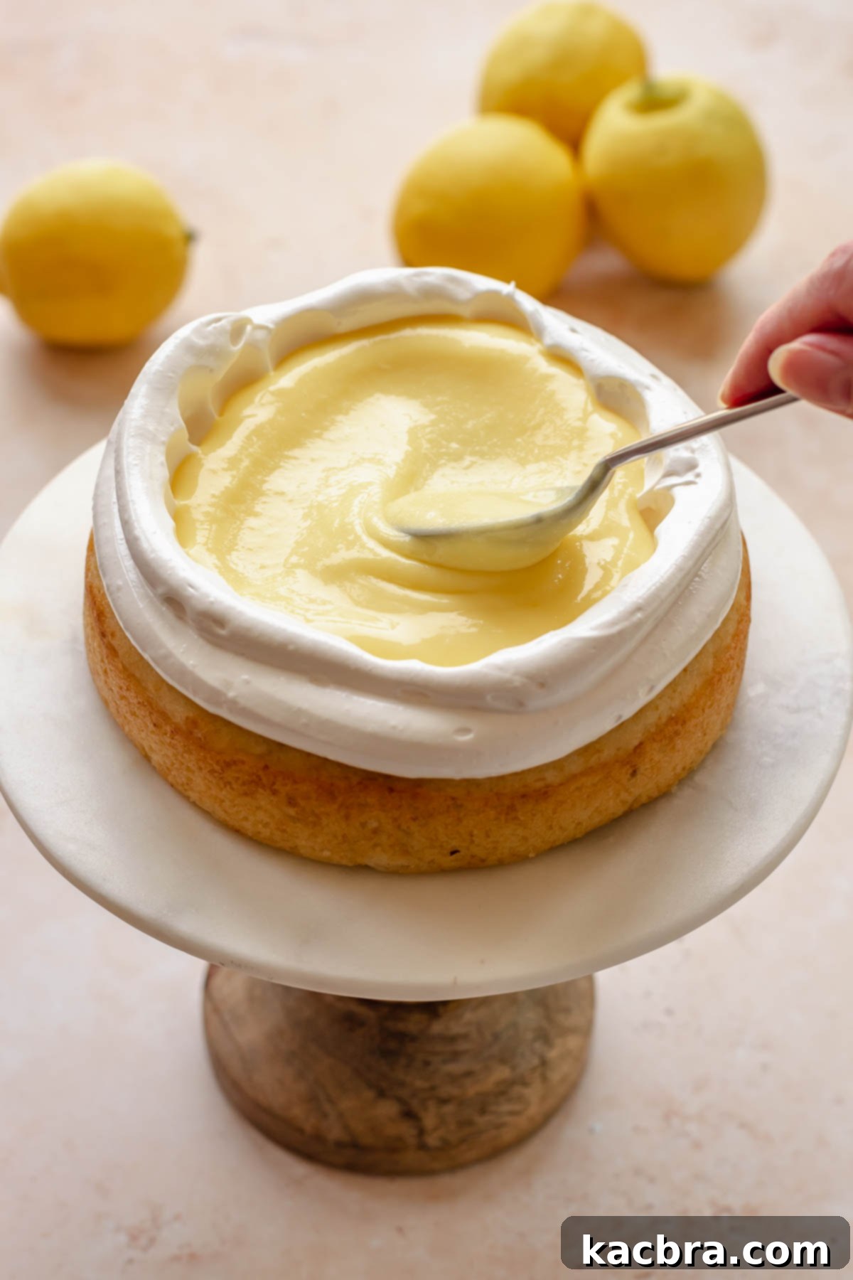 A spoon adds lemon curd into the middle of the cake.