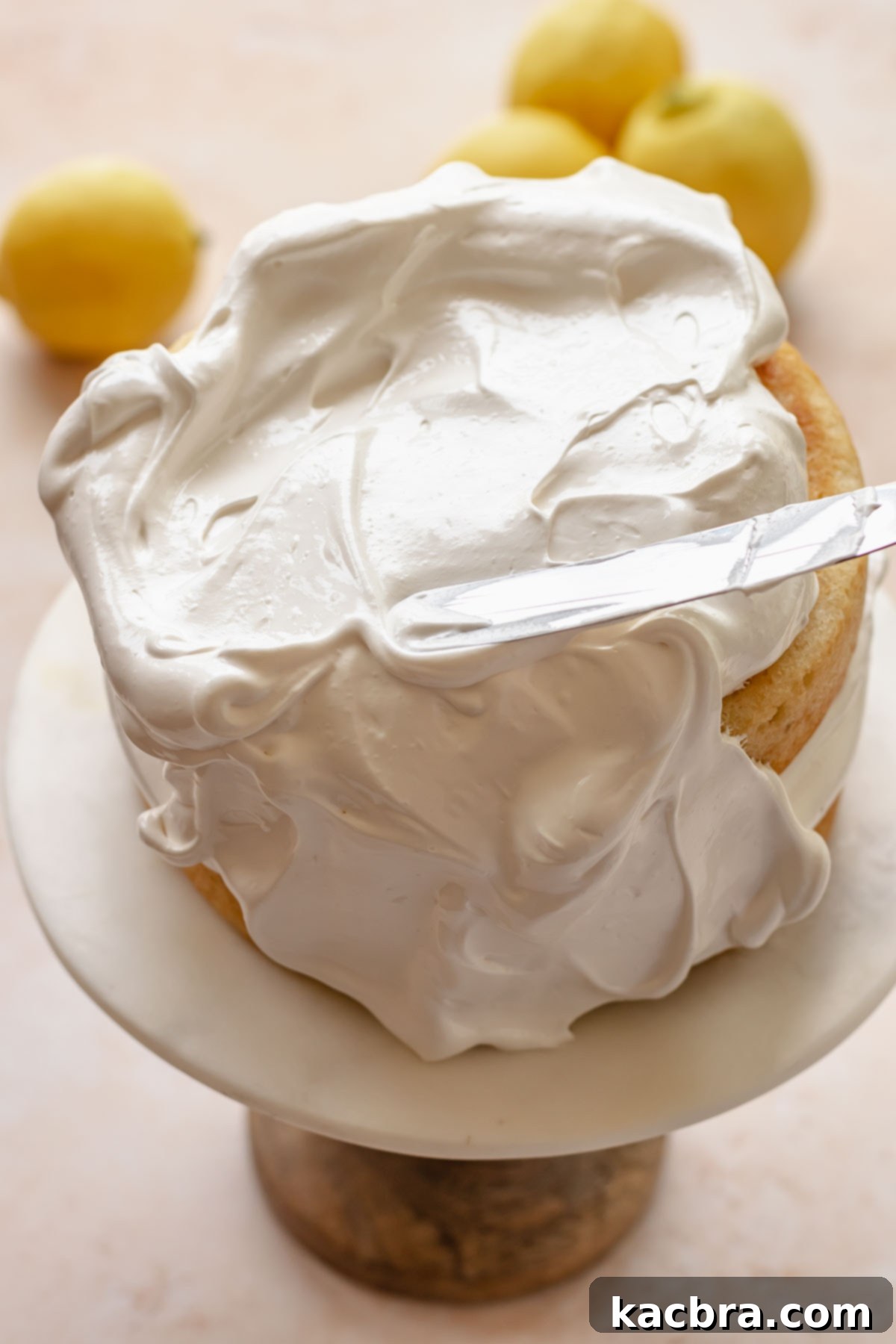 A spatula adds Swiss meringue to cover the cake layers.