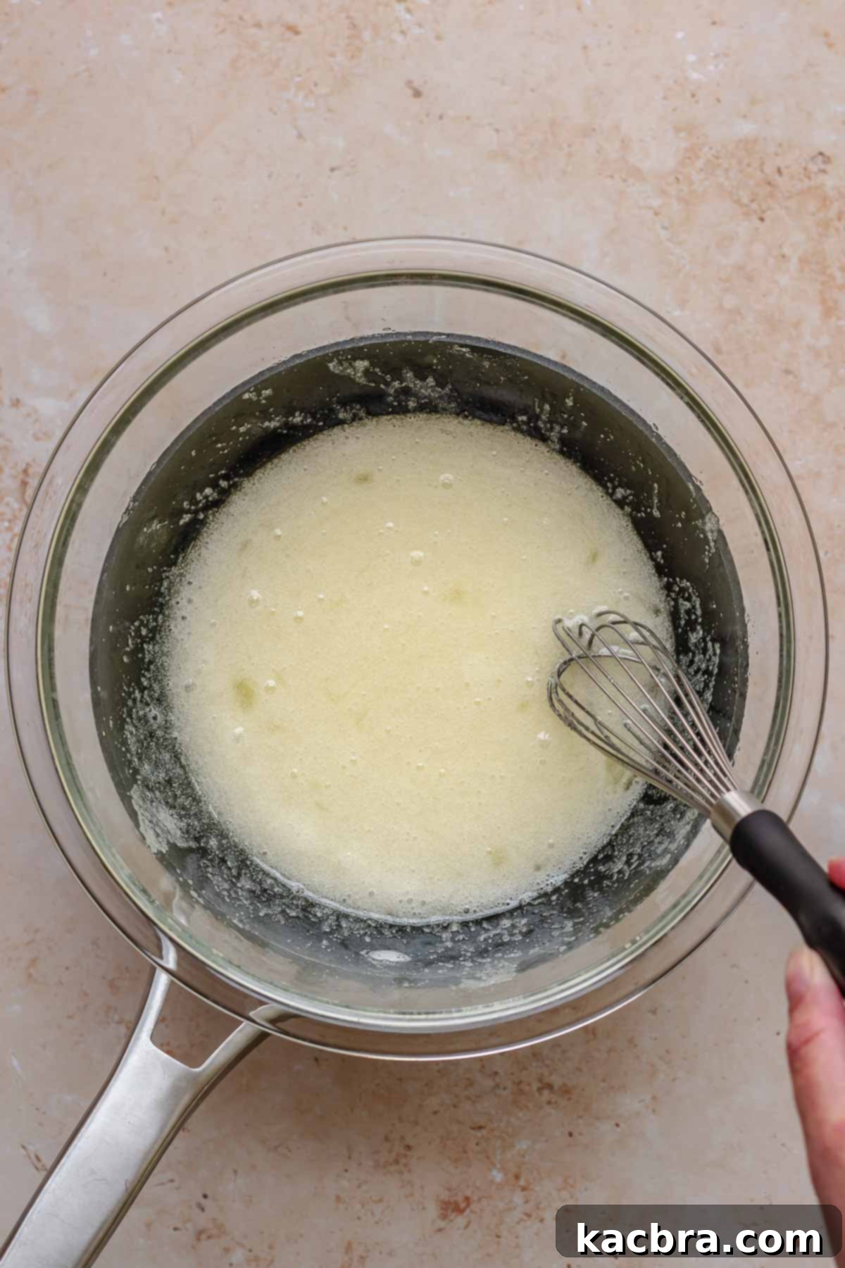 A whisk mixes egg whites and sugar in a Bain Marie.