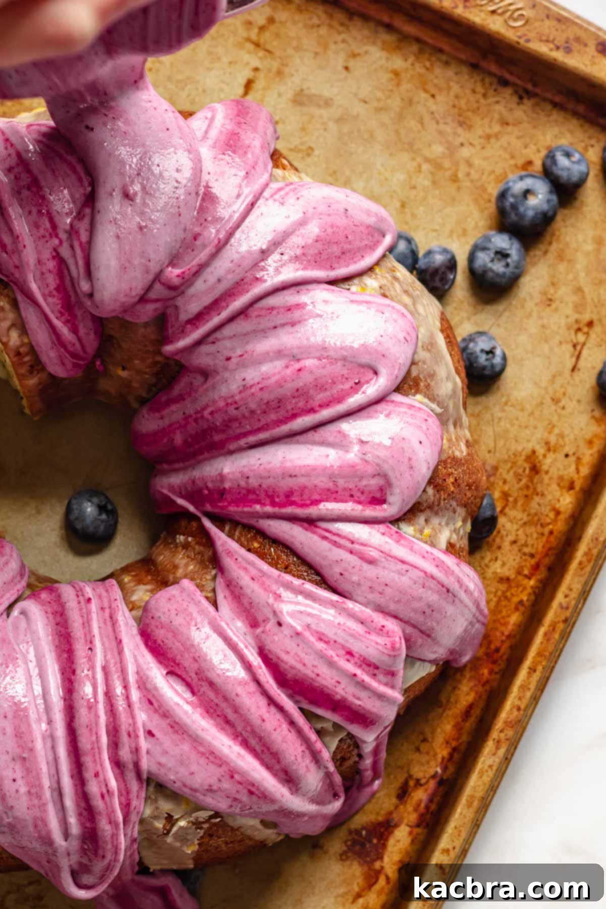 Marbled blueberry glaze being poured onto a Bundt Cake.