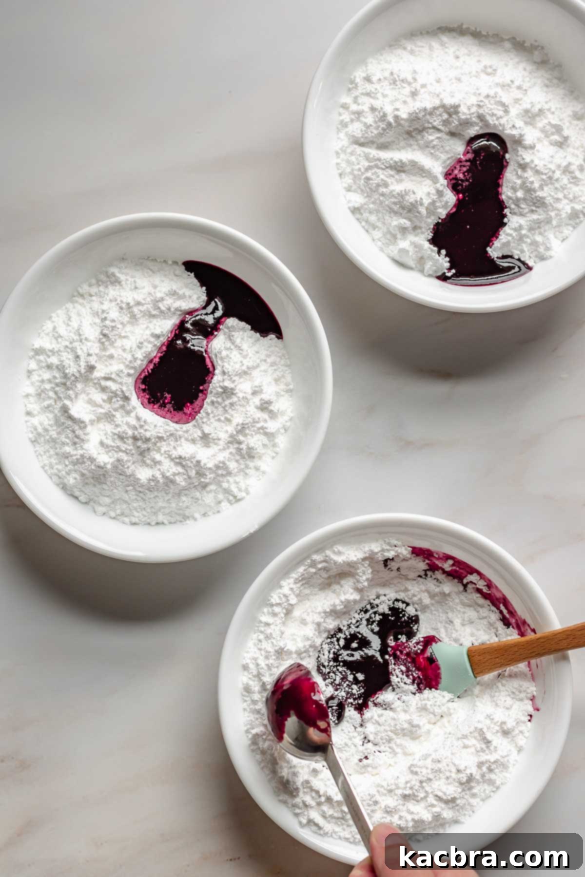 Bowls of powdered sugar with blueberry puree in them.