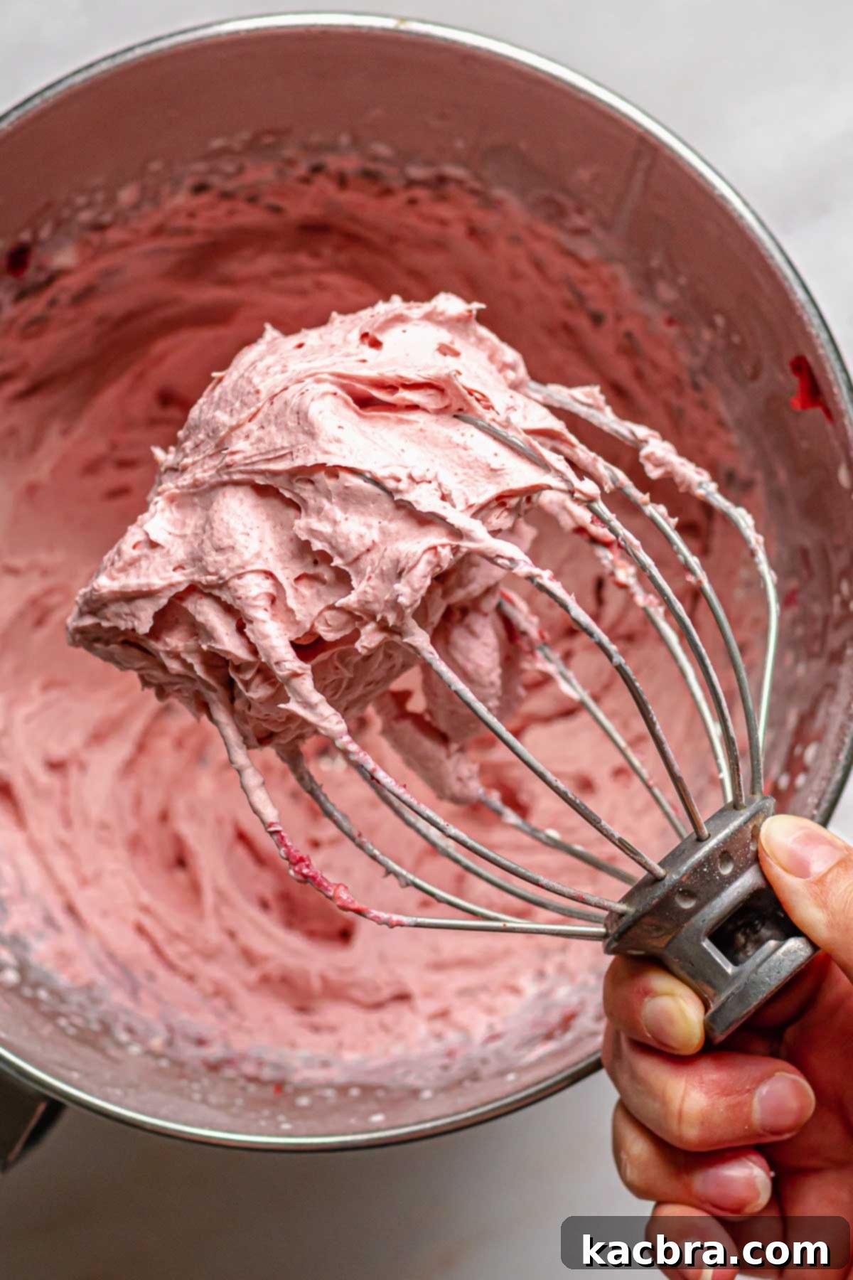 Blushing Strawberry Delights 11 A whisk coated in light and fluffy freeze-dried strawberry frosting, illustrating the perfect whipped consistency.