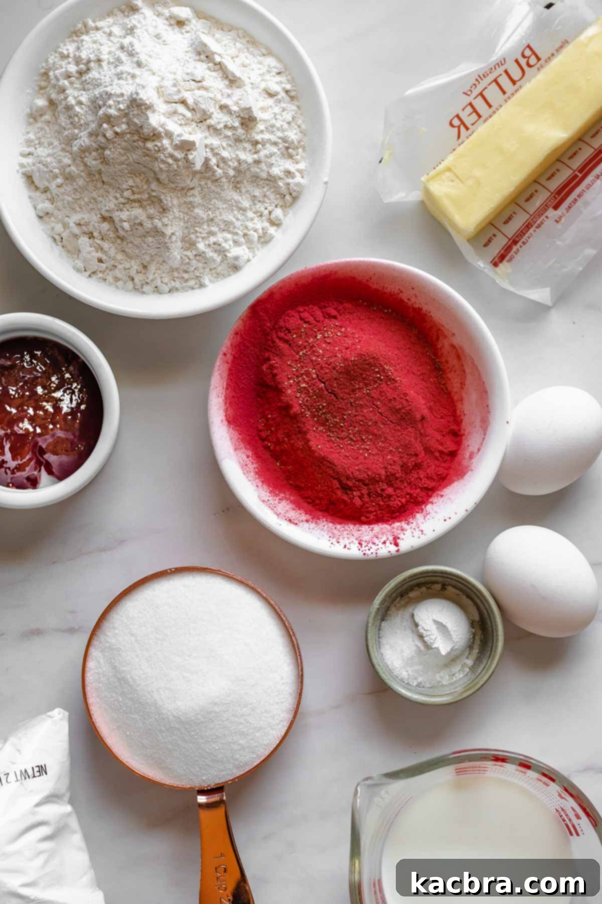 Blushing Strawberry Delights 4 A selection of key ingredients laid out for making strawberry whoopie pies, including flour, butter, strawberry jam, freeze-dried strawberries, eggs, leavening agents, various sugars, and milk.