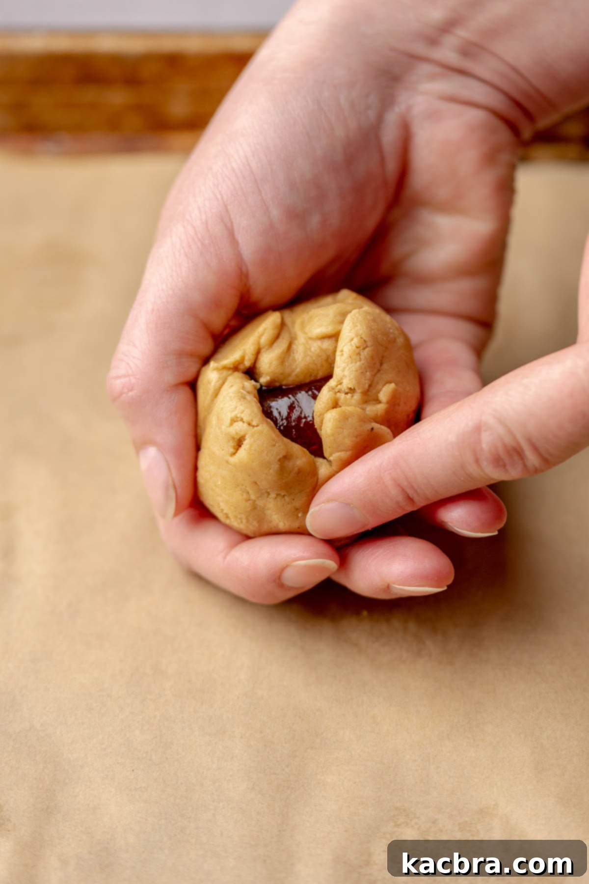 Jammy Peanut Butter Delights 12 Two hands folding peanut butter cookie dough around a dollop of jelly, sealing it in.