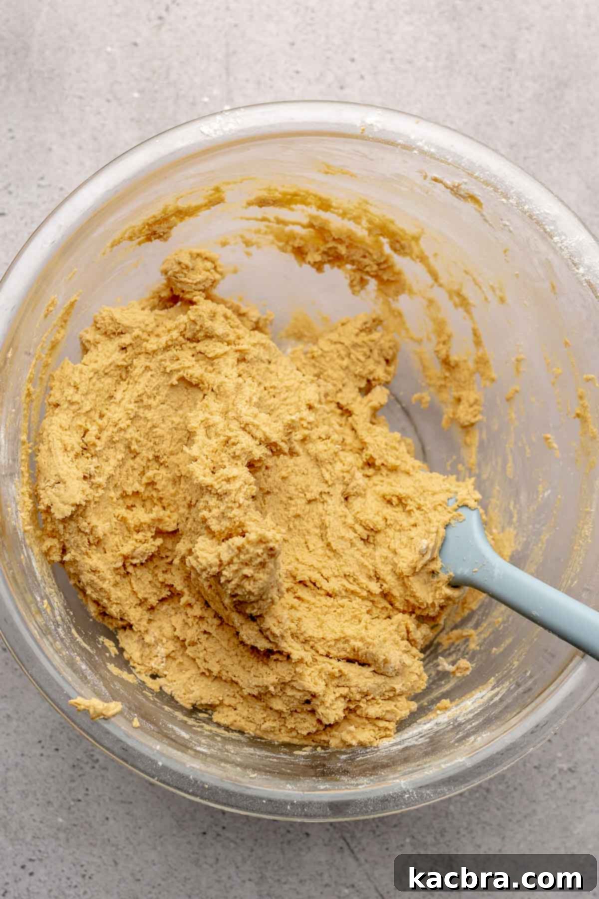 Jammy Peanut Butter Delights 7 Finished peanut butter cookie dough in a mixing bowl with a spatula resting on the side.