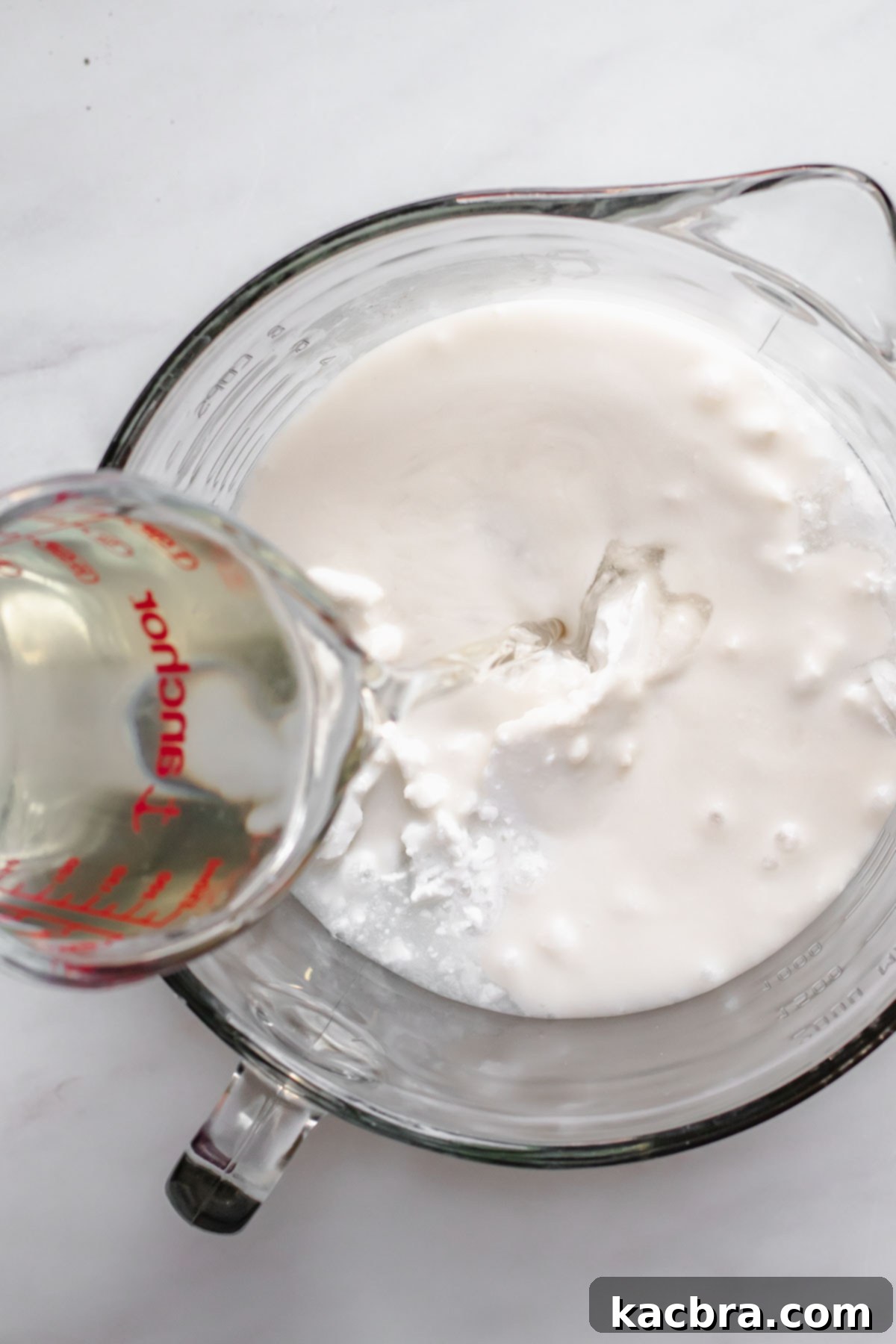 Coconut simple syrup being poured into a bowl with coconut milk.