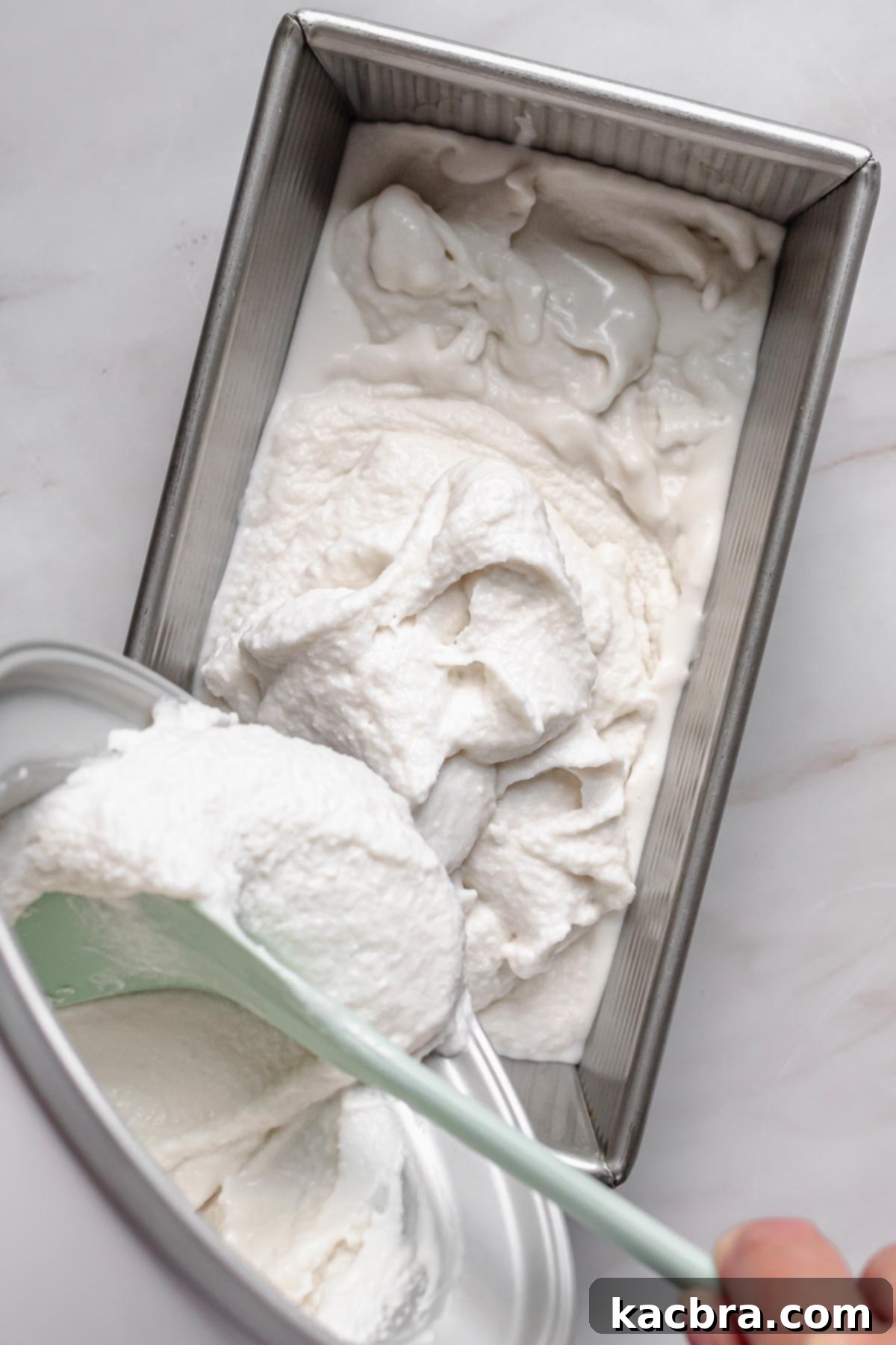 Soft-set coconut sorbet being transferred from the ice cream machine into a metal pan for final freezing.