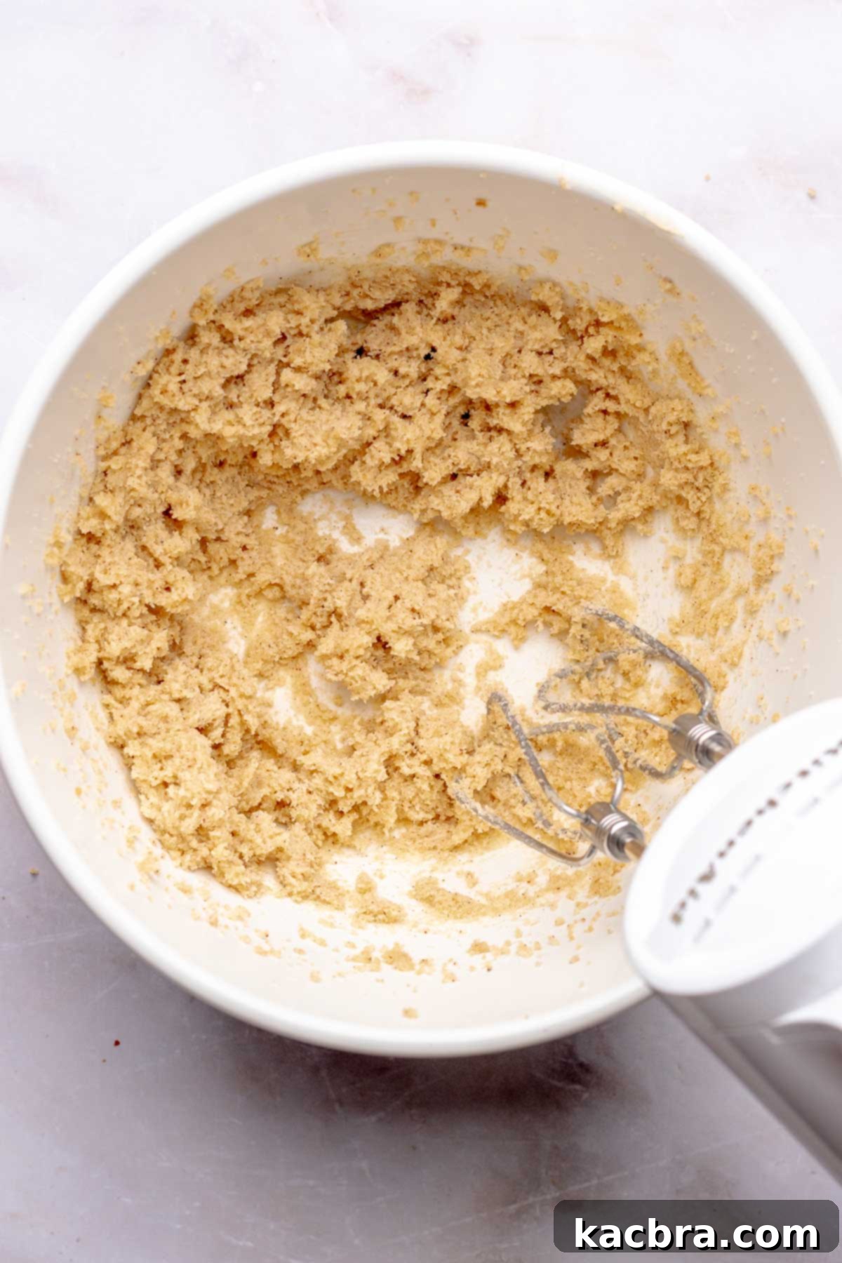 A hand mixer creams together butter and sugar in a bowl.
