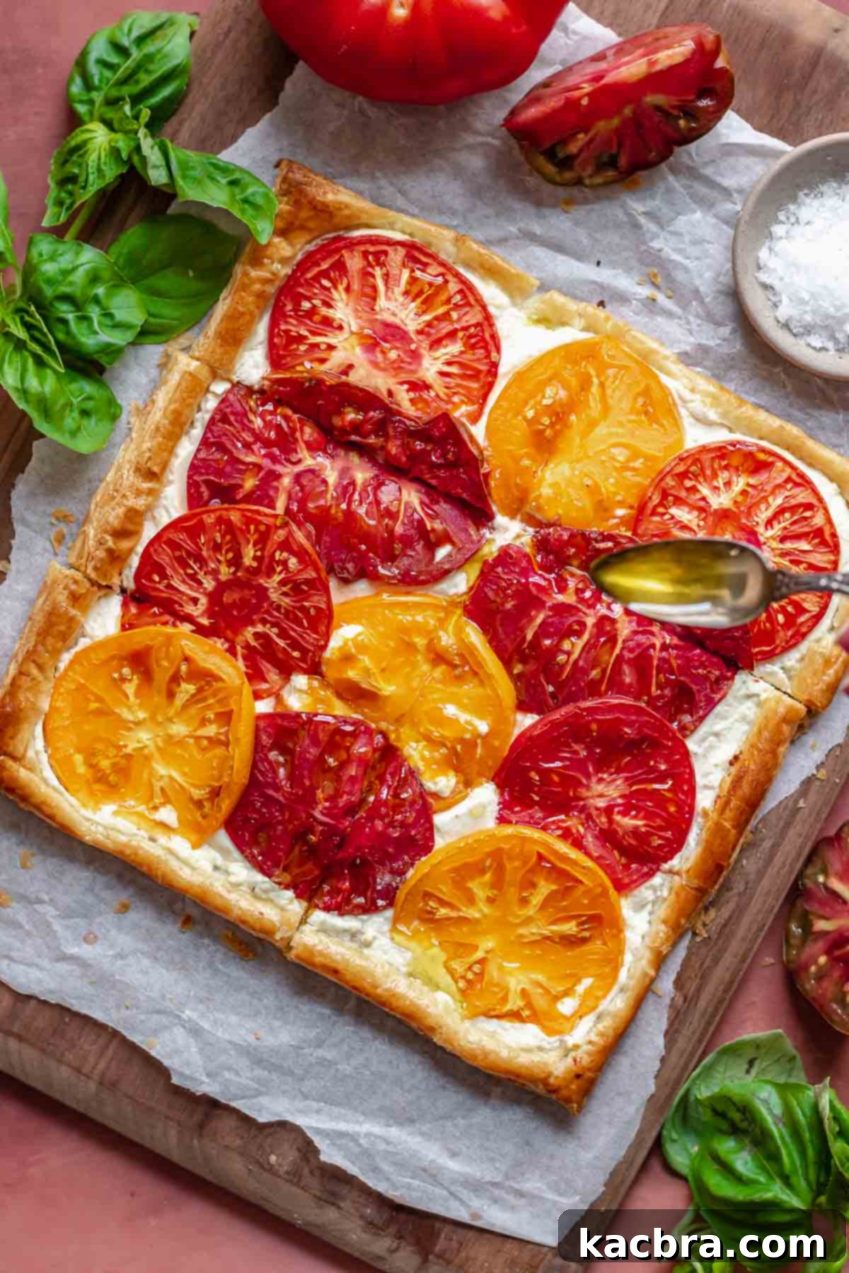 Rustic Tomato and Double Cheese Puff Pastry Tart 8 A spoon drizzles olive oil onto the freshly baked tart.