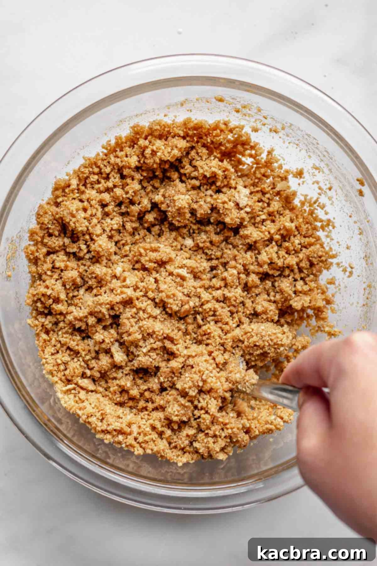 Mixing graham cracker crumbs, melted butter, and sugar together with a fork in a bowl.