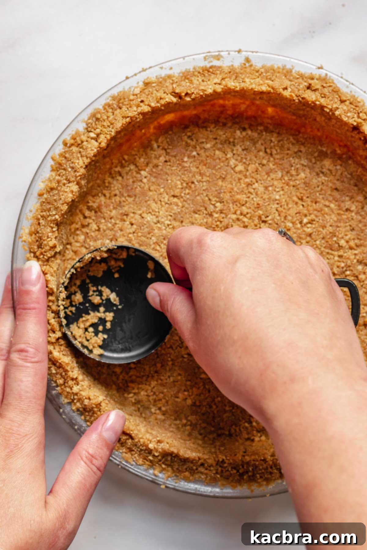Pressing the moistened graham cracker crumbs firmly into the bottom and sides of a pie dish.