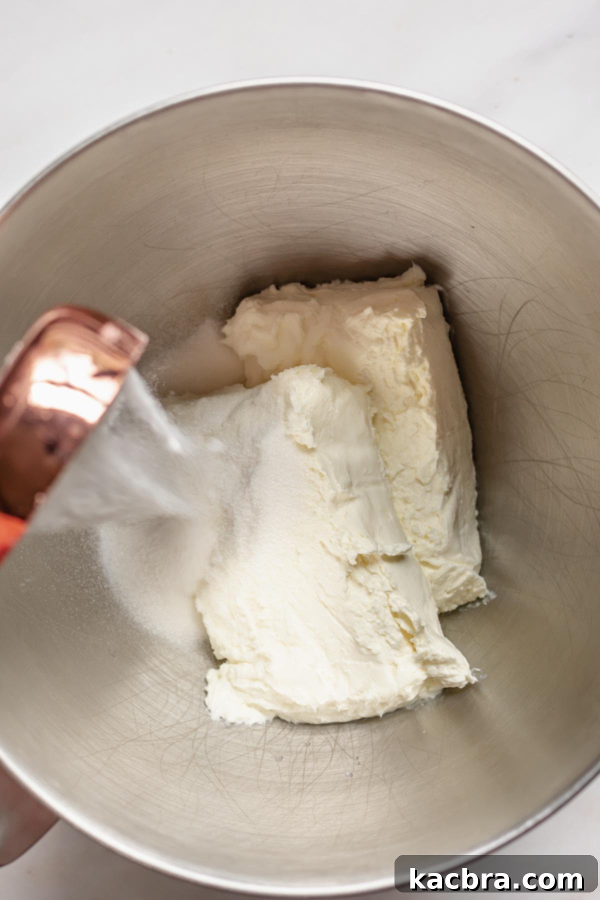 Granulated sugar and softened cream cheese in the bowl of a stand mixer.