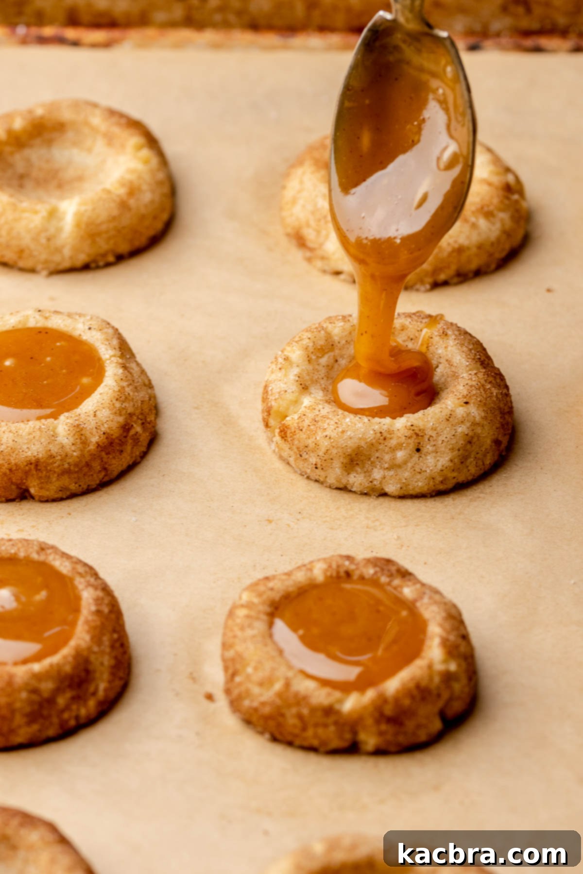 A spoon drizzles apple cider caramel into a cookie.