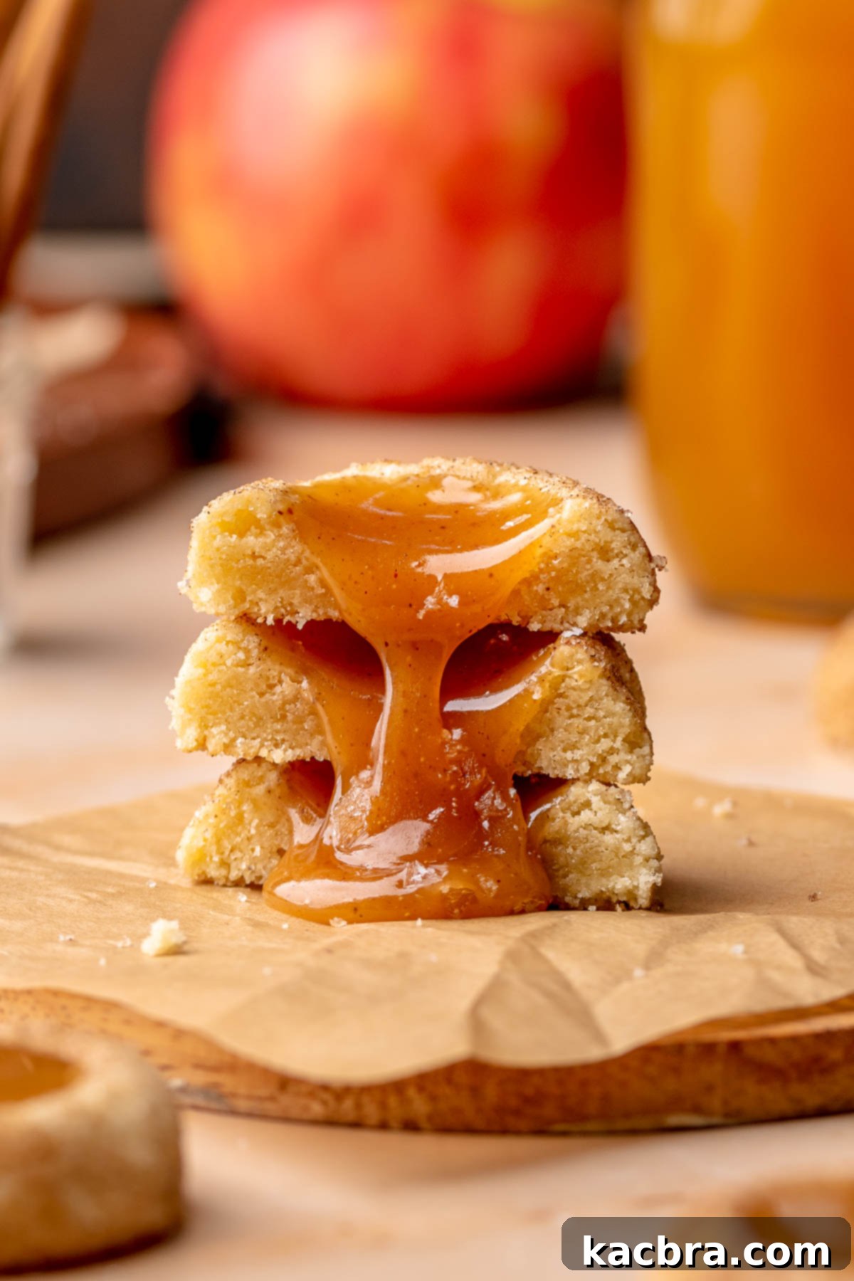 A stack of apple cider cookies cut in half with caramel oozing down the stack.