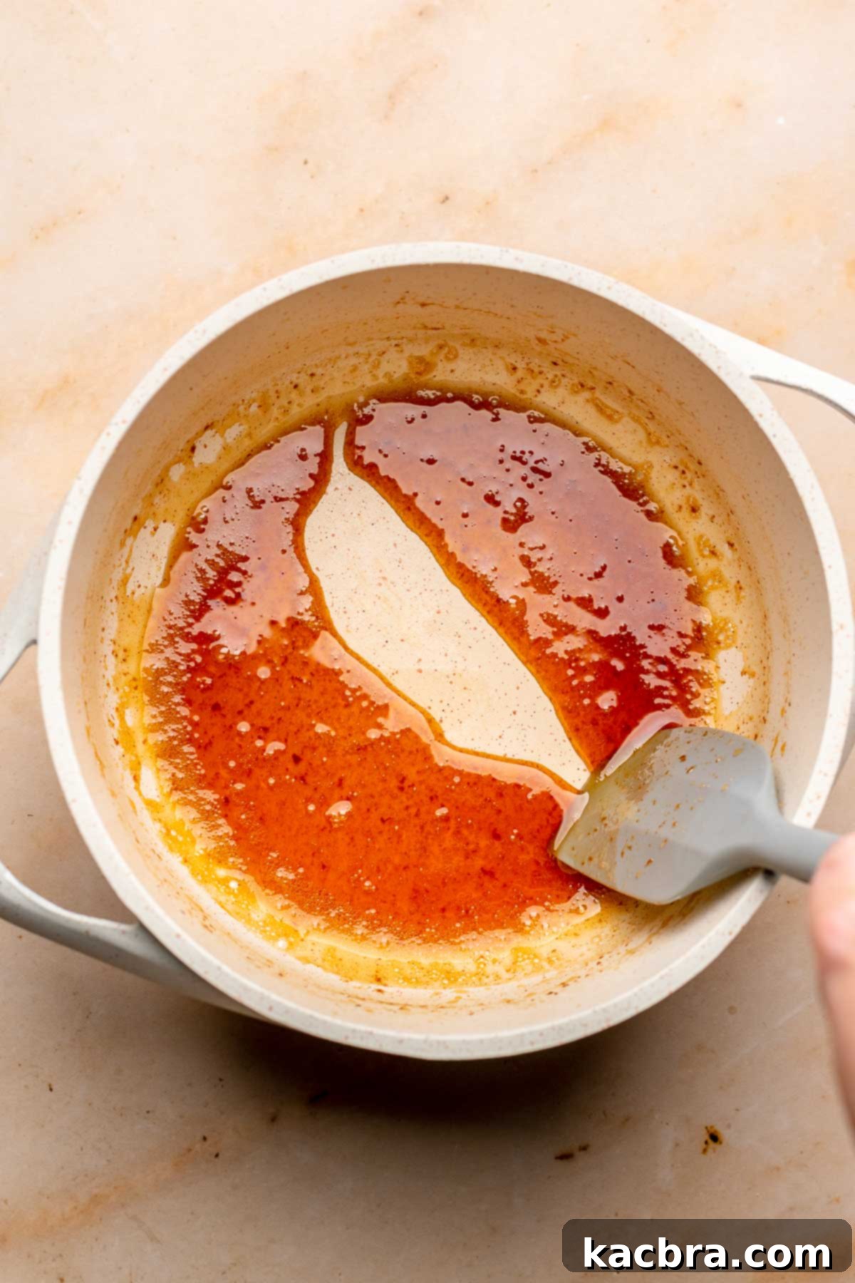 A spatula drags through a pot of reduced apple cider.