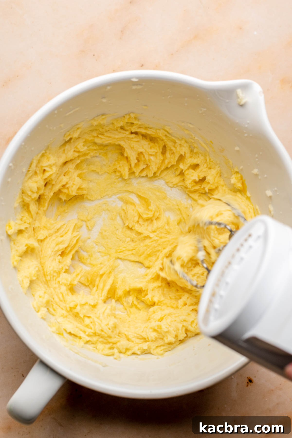 A hand mixer beats cookie dough in a bowl.