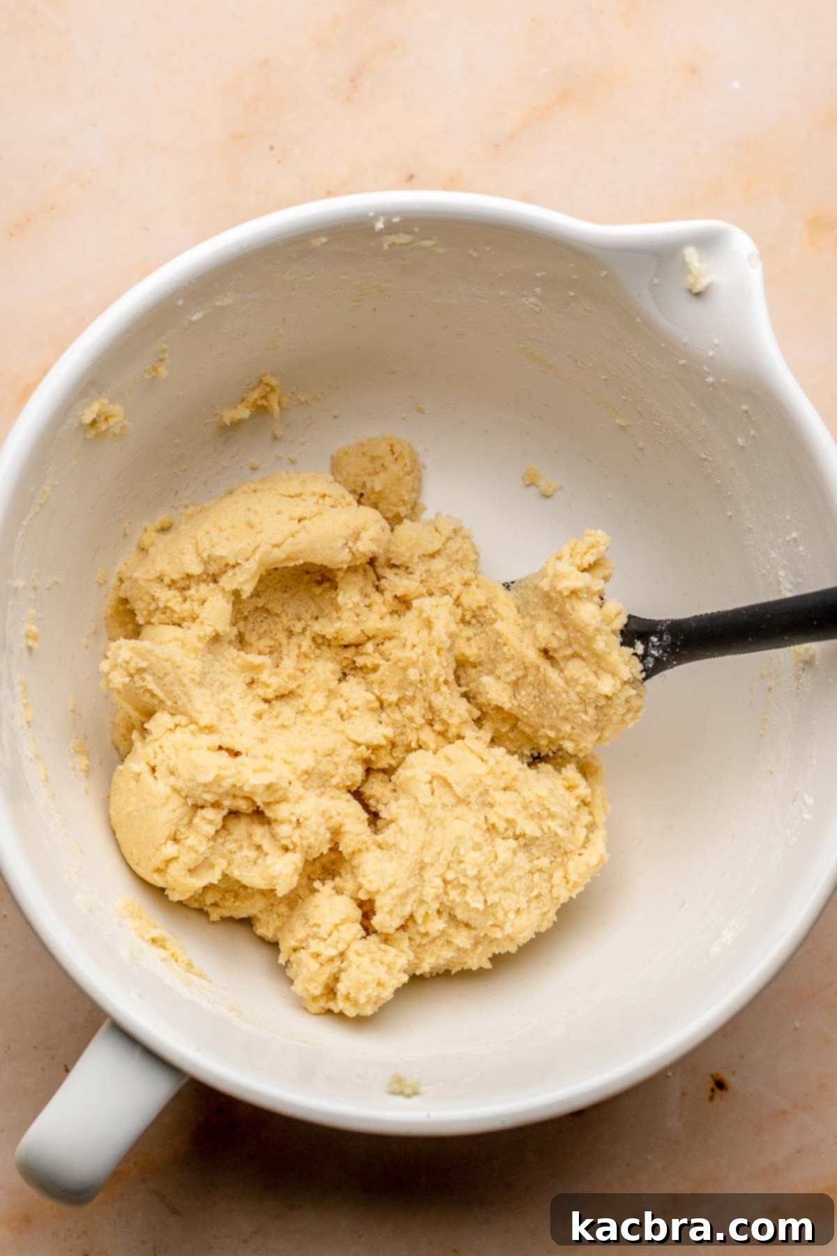 A clump of cookie dough in a bowl with a spatula.