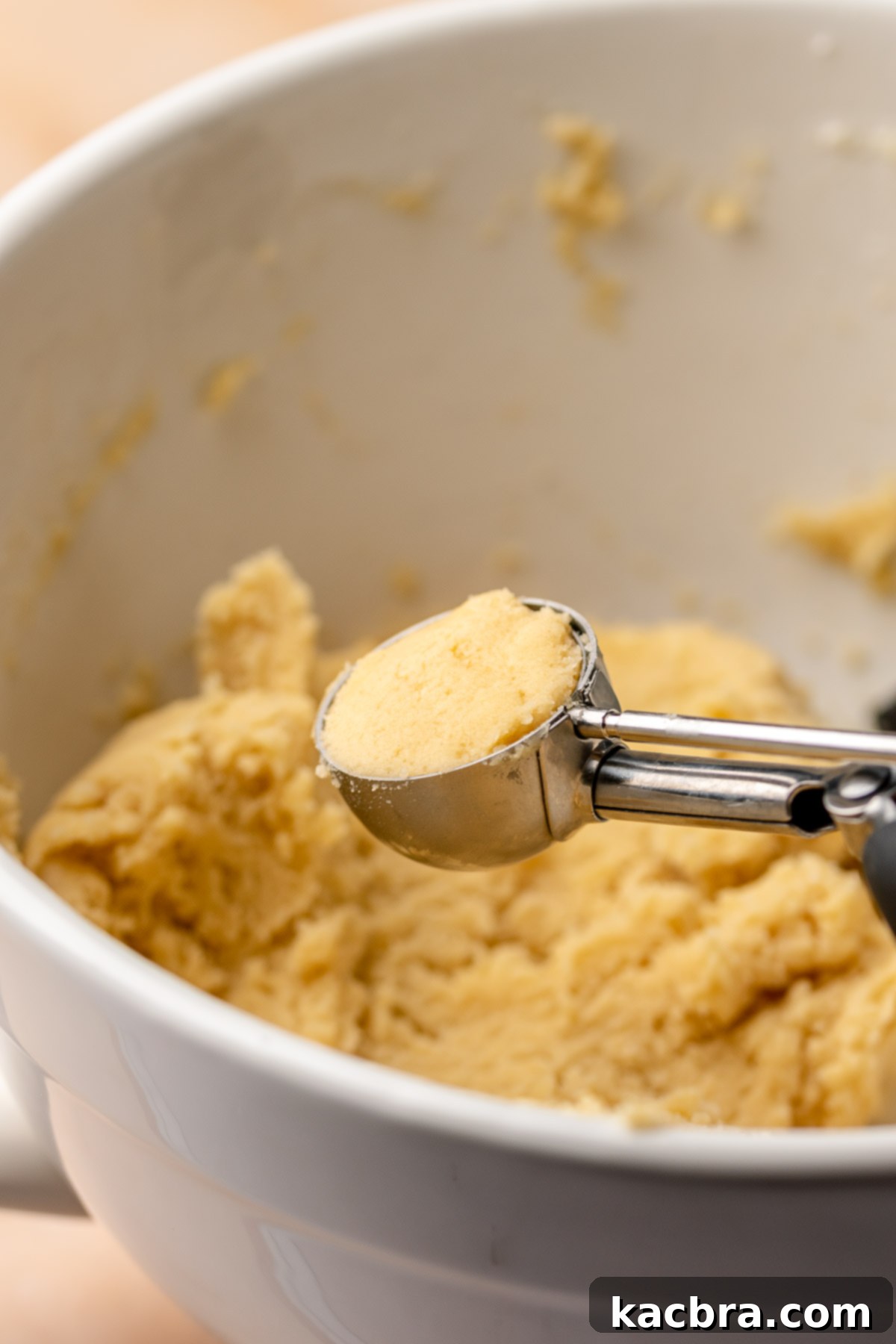 A cookie scoop holds cookie dough in the scoop.