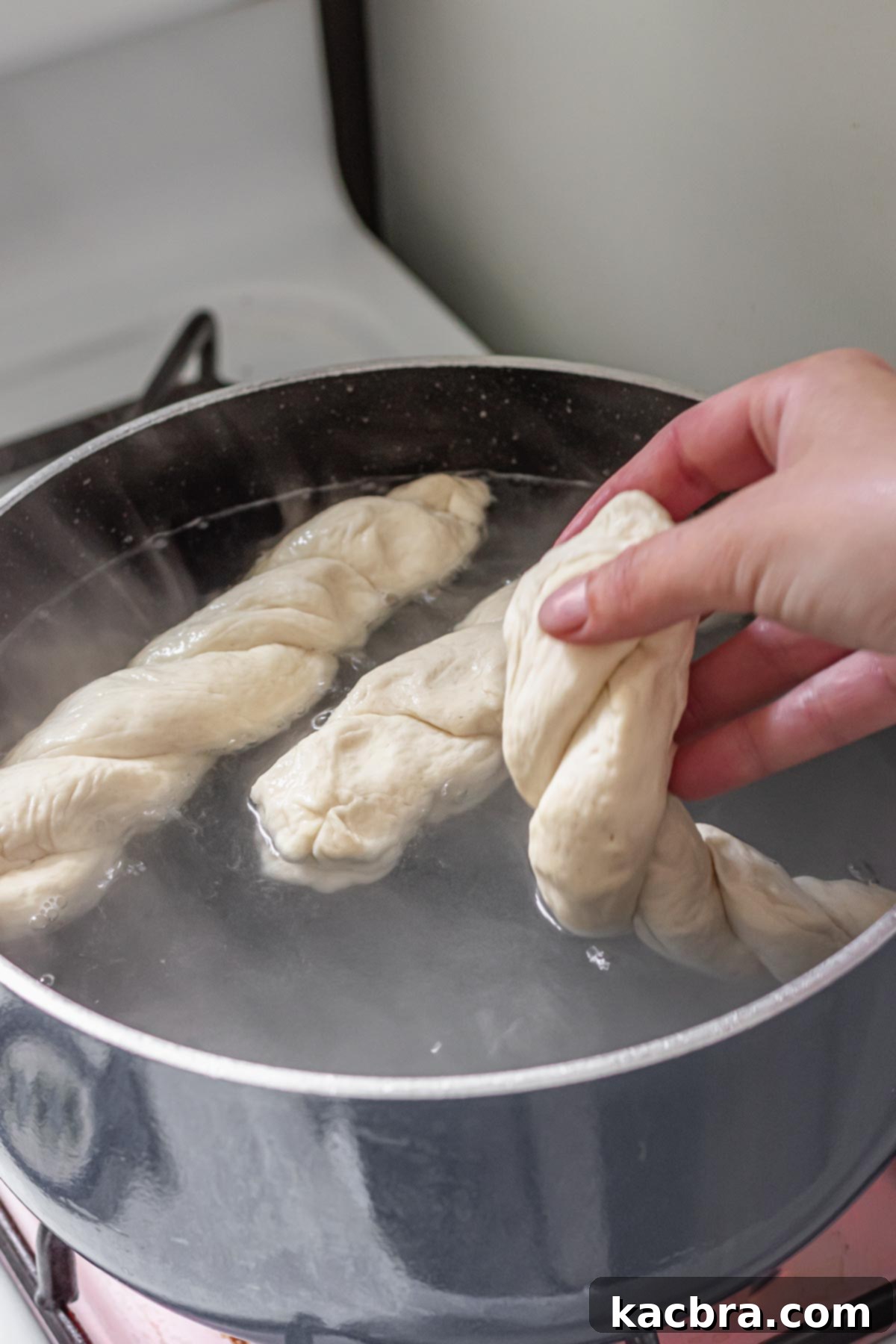 Adding pretzel dough to a baking soda bath.