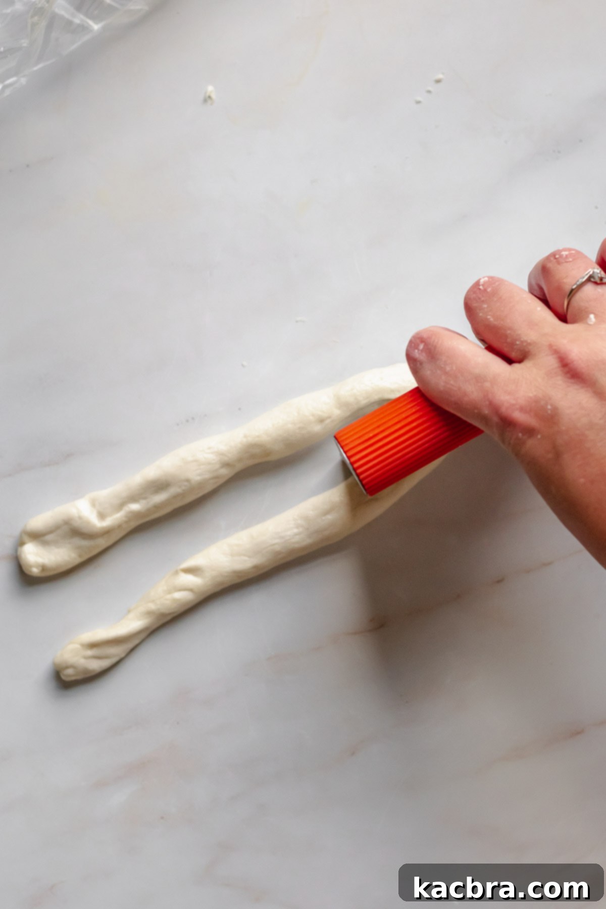 Cutting a log of pretzel dough.