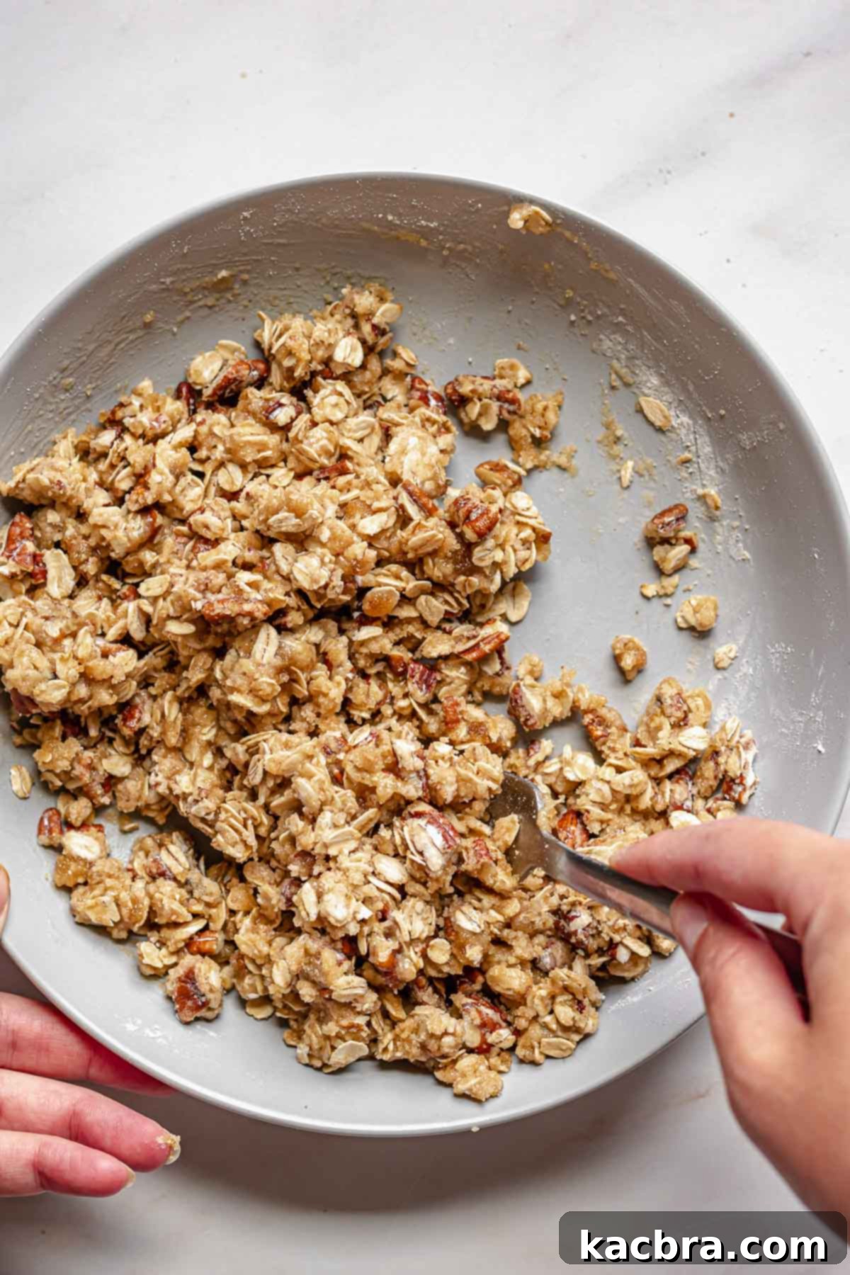 Mixing together streusel topping ingredients in a bowl with a fork, showing the crumbly texture forming.