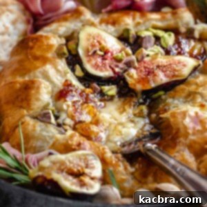 Close up of baked brie with fig jam and a serving being removed.