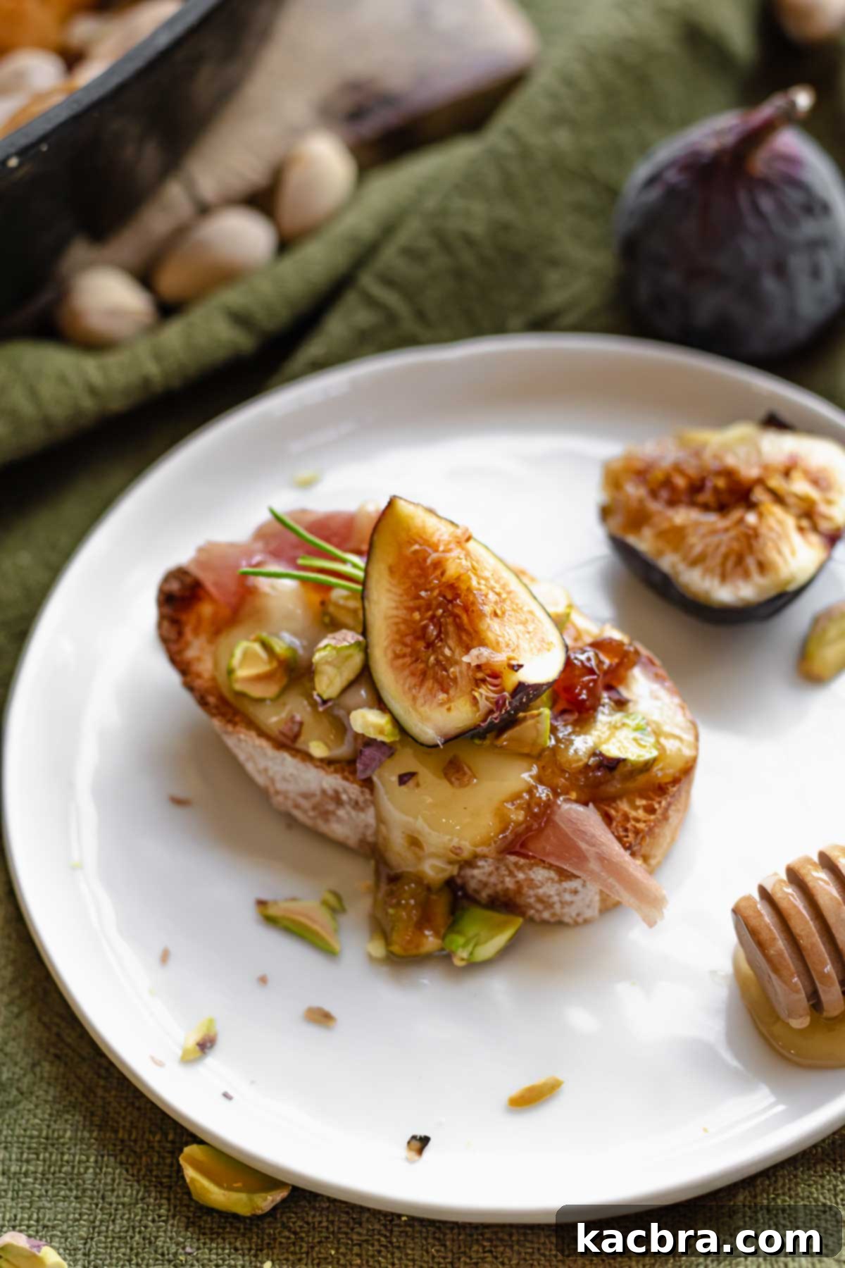 A perfectly baked slice of brie with fig jam rests on a toasted baguette slice, ready to be enjoyed.