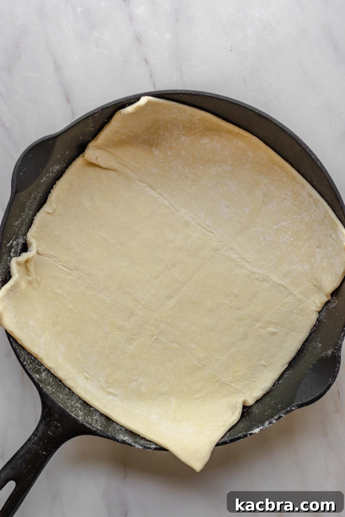 Puff pastry carefully placed in a cast iron skillet, ready for the brie.